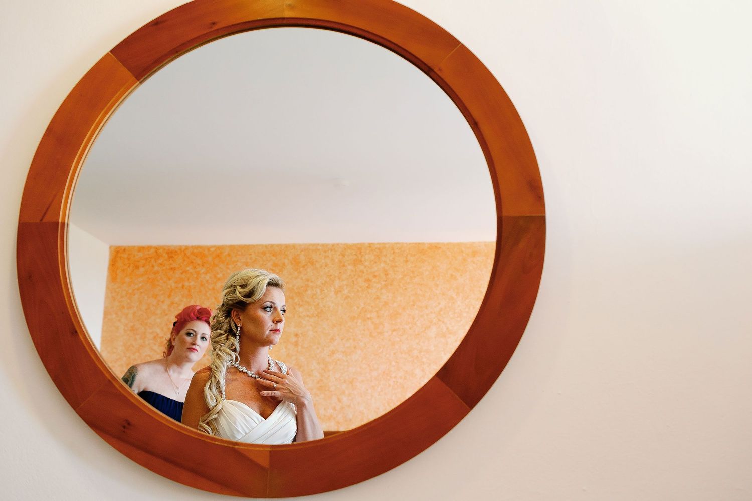 Carly checking her necklace in a round mirror before the ceremony