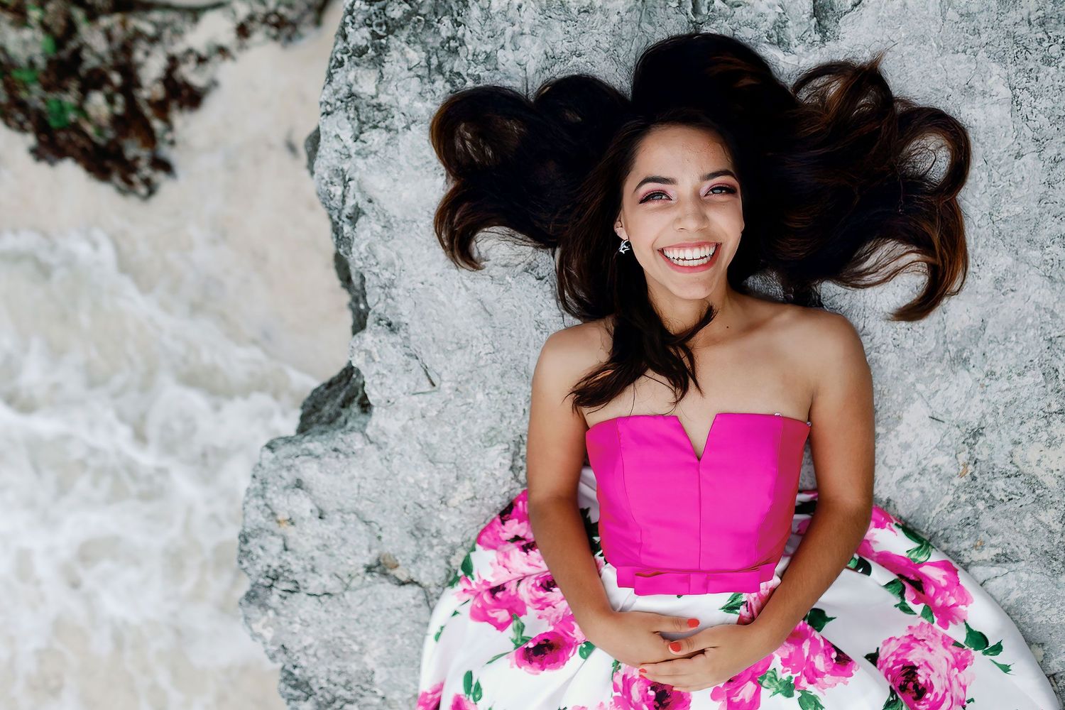 Sweet 15 portrait session in Cancun with a floral dress, natural limestone rocks, and the turquoise Caribbean coast.