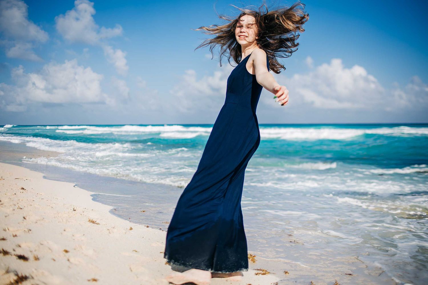 Senior portraits in Cancun with a navy blue dress, turquoise Caribbean water, white sand, and natural beach scenery.