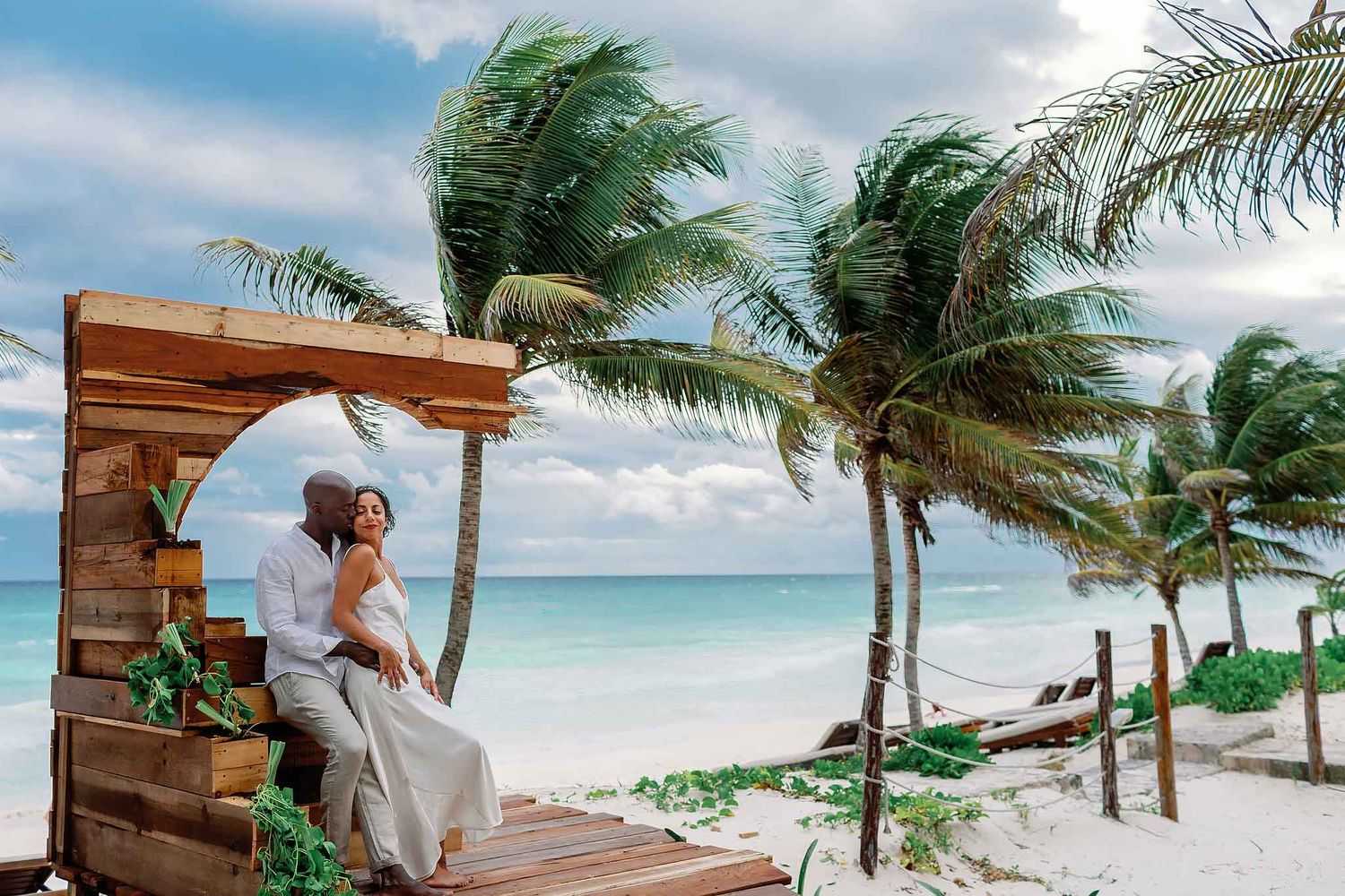 Romantic couple portrait in Tulum on the beach with palm trees, ocean breeze, and Caribbean sea backdrop in Riviera Maya