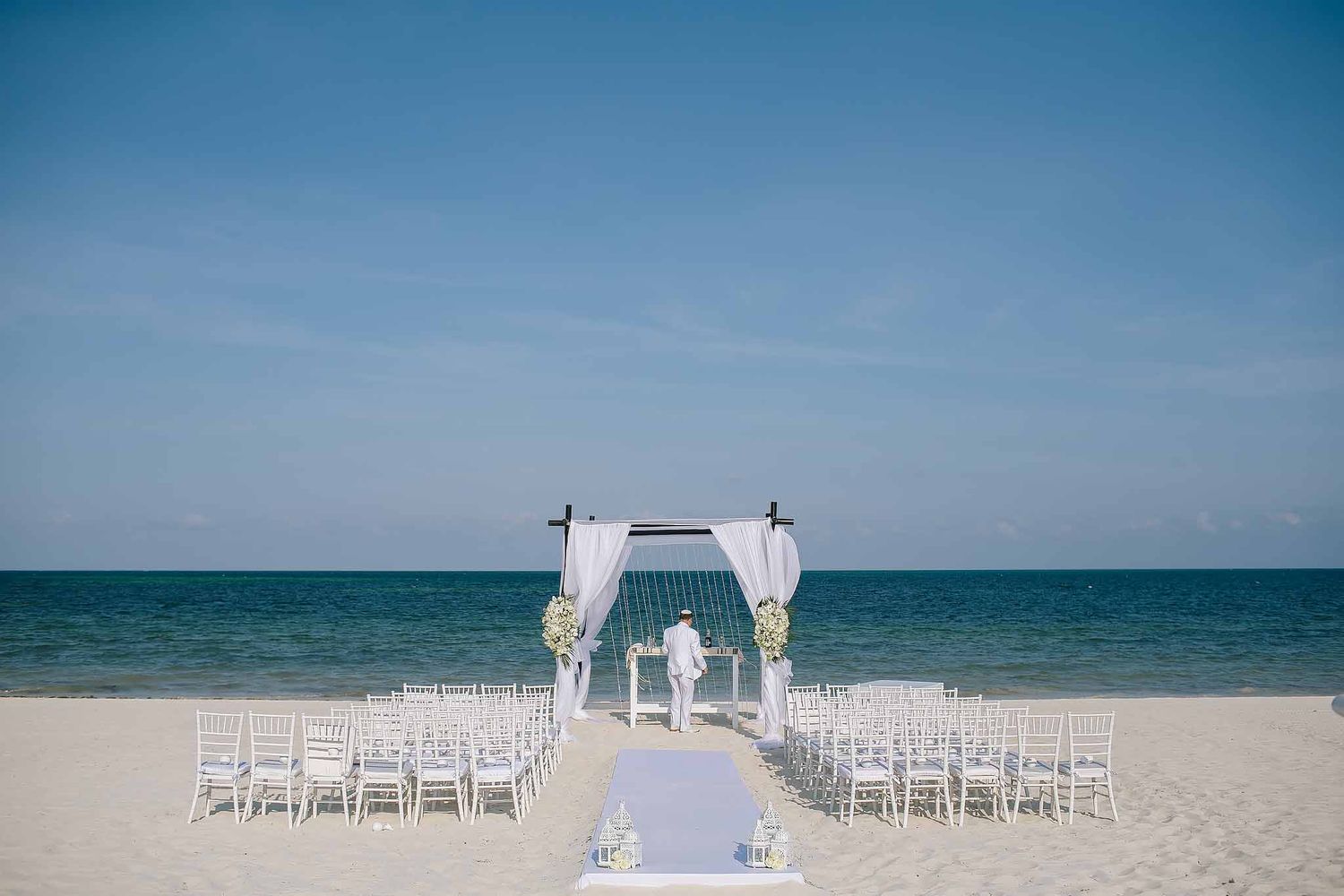 Elegant beach wedding ceremony setup at TRS Coral Hotel Costa Mujeres with white aisle, oceanfront altar, and Caribbean views.