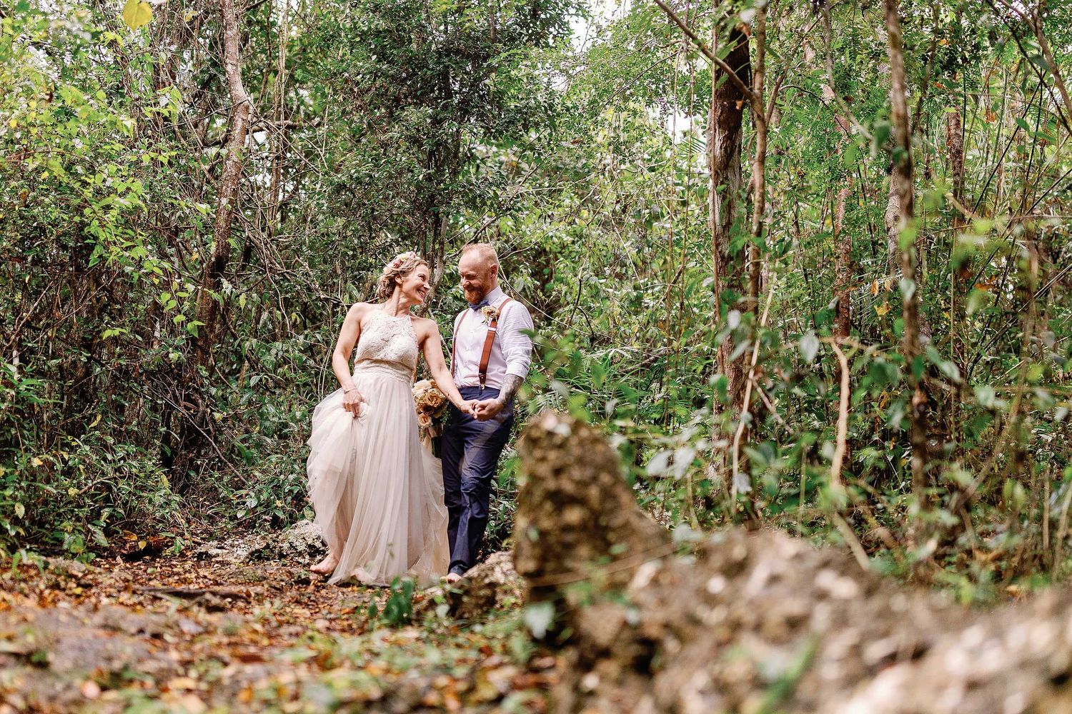 Jeff and Veronica walking hand in hand through the tropical jungle during their wedding portraits at Cenote Hats’uts near Playa del Carmen.
