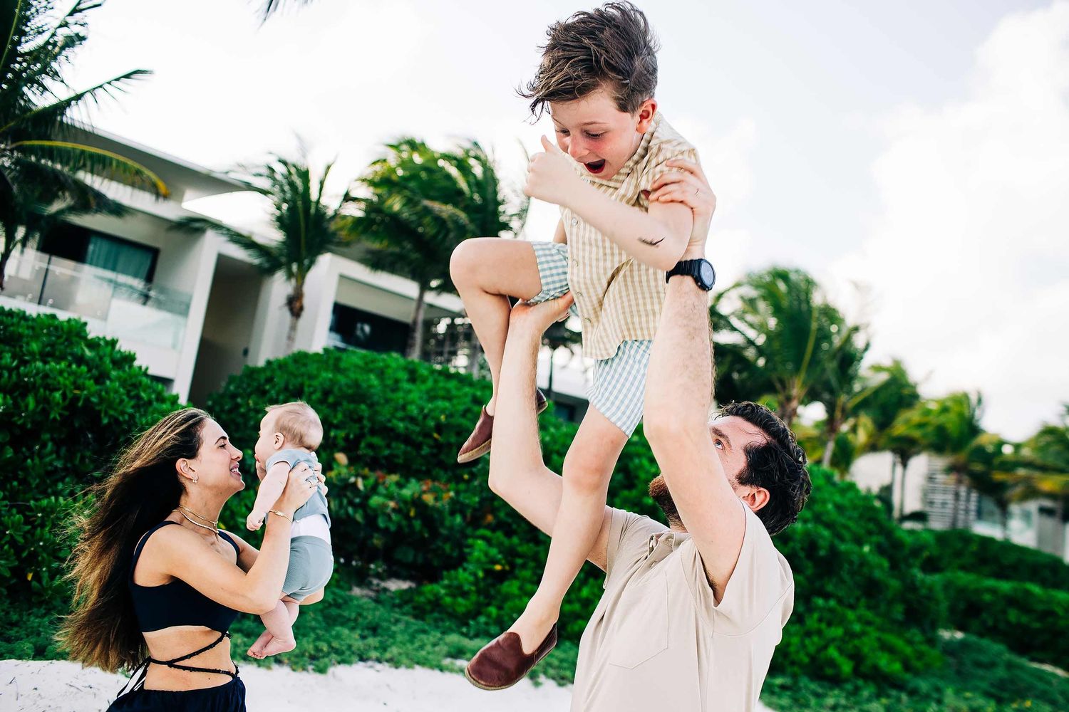 Parents lifting their child during a playful family photography session at Fairmont Mayakoba Riviera Maya.