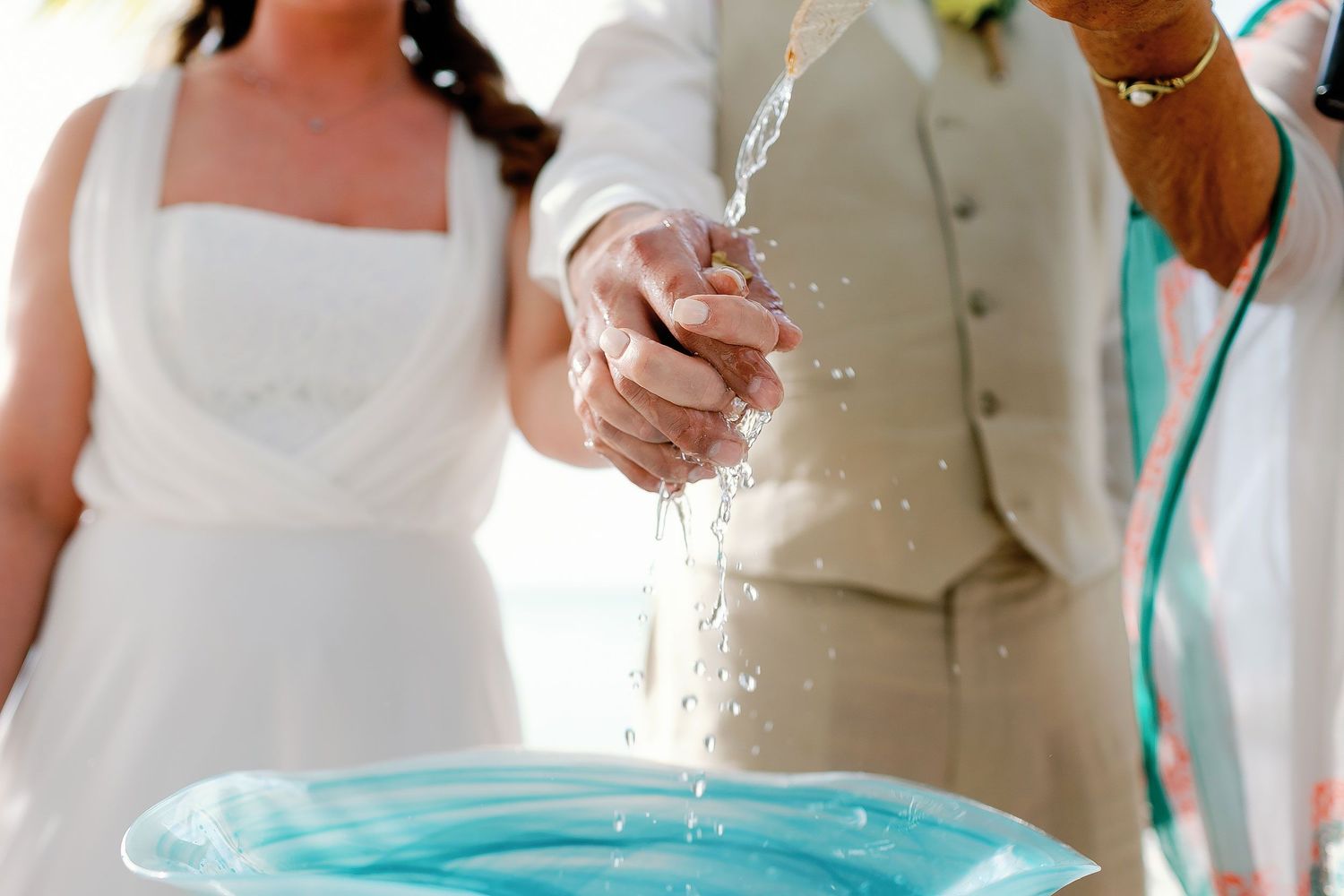 Water is poured over Li and Carlos’s joined hands during their Playa Norte wedding ceremony.