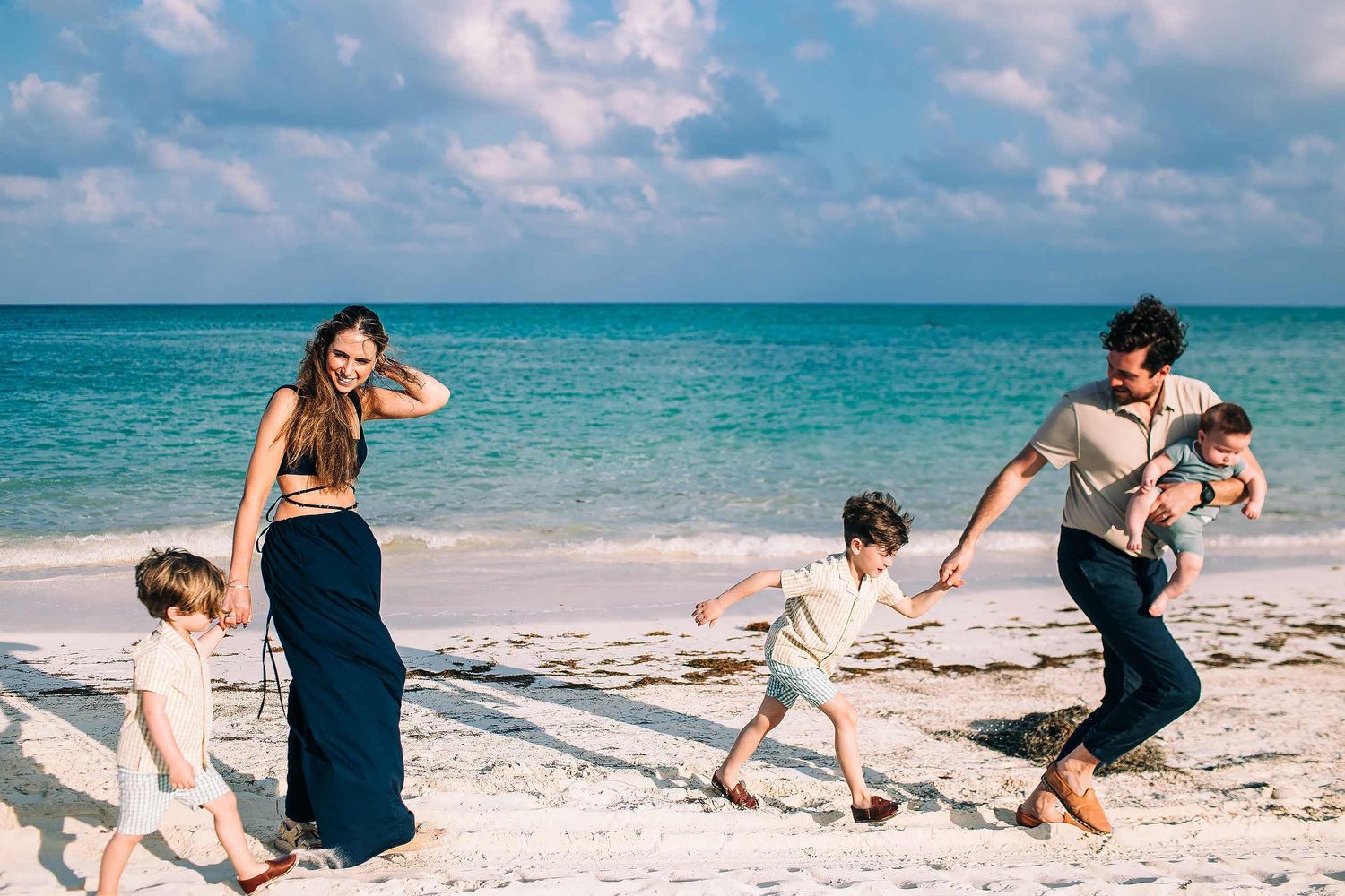 Family walking together on the beach during a sunset family photography session at Fairmont Mayakoba Playa del Carmen.