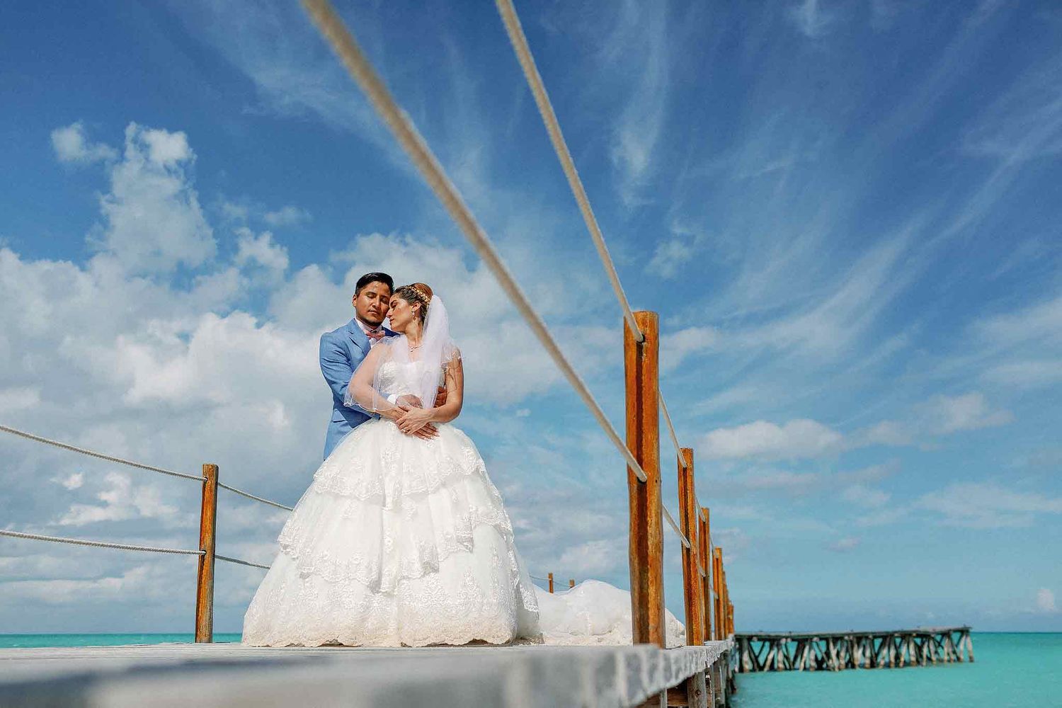 Creative wedding portrait at Live Aqua Cancun on a Caribbean pier with turquoise water and dramatic sky in Riviera Maya.