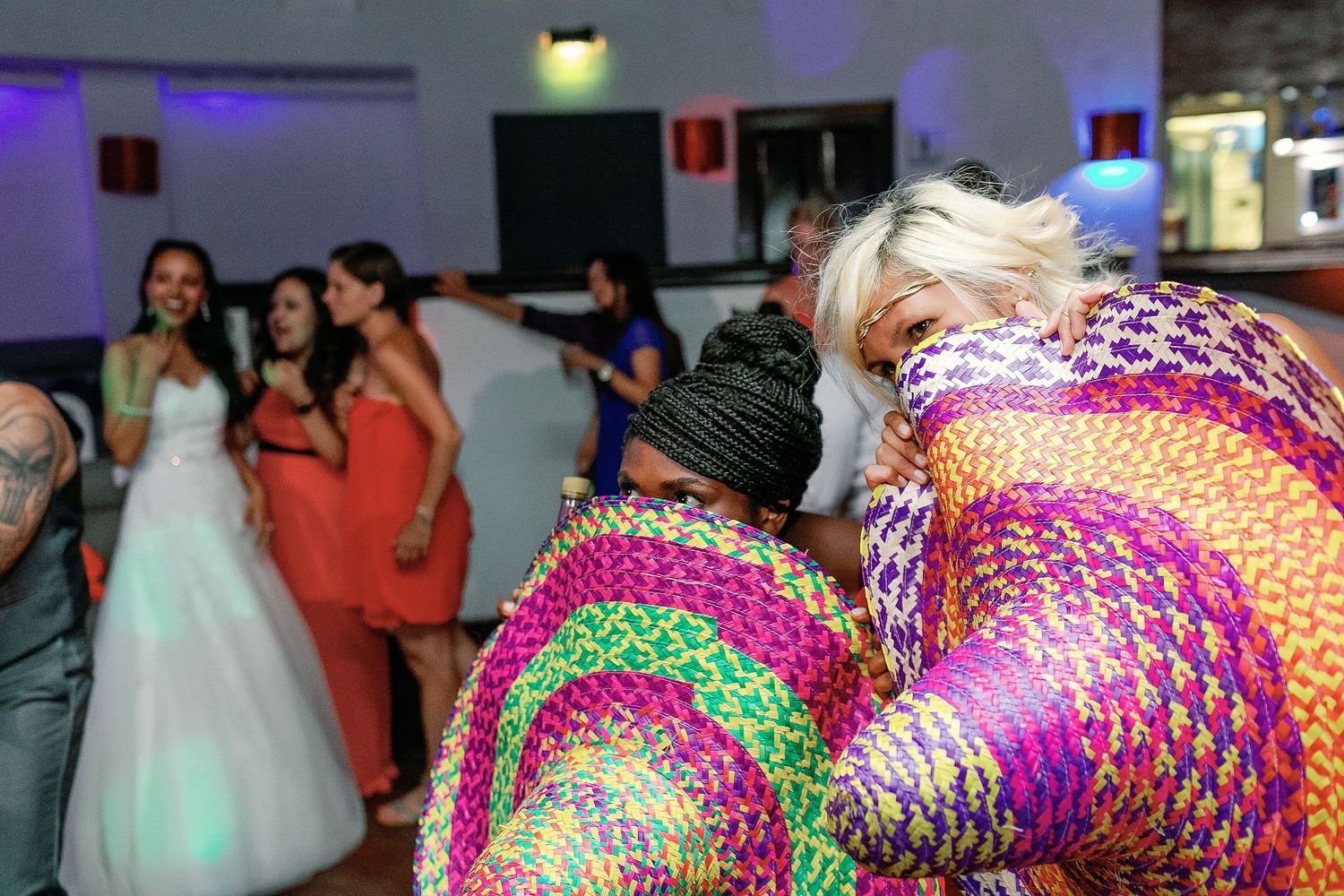 Guests playfully hide behind colorful Mexican sombreros during the wedding reception.