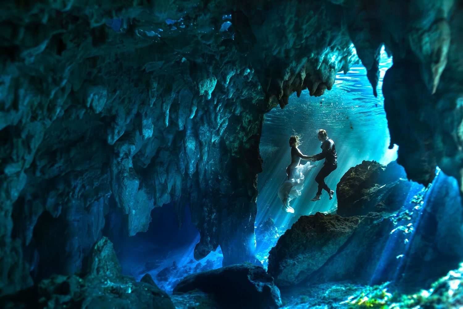 Carly and Scott holding hands underwater inside a Riviera Maya cavern