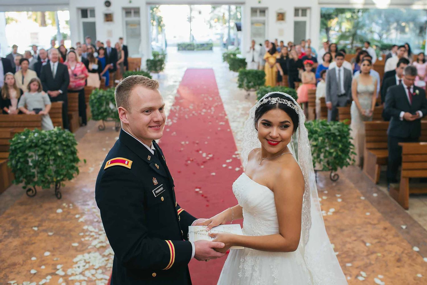 Bride and groom during Catholic wedding ceremony at Cristo Resucitado Chapel in Cancun Hotel Zone with guests and red aisle
