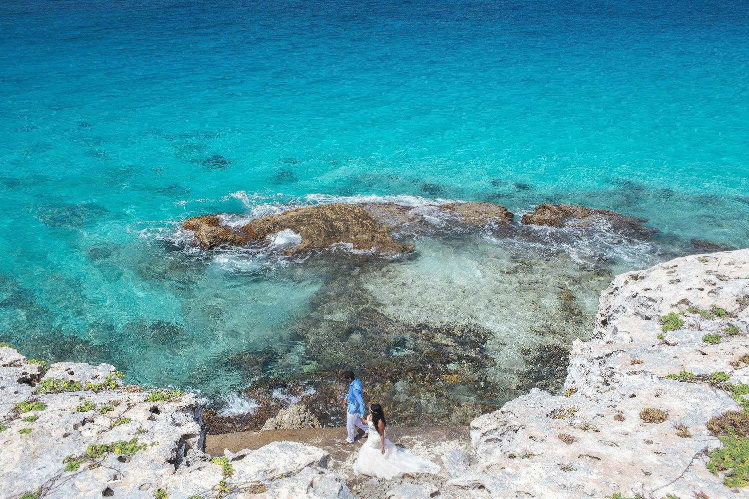 Creative wedding portrait in Isla Mujeres featuring dramatic limestone cliffs and crystal-clear Caribbean waters near Izla Hotel.