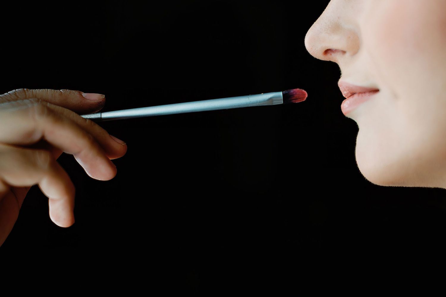 Close-up of a makeup artist applying lipstick to the bride as she prepares for her wedding at Generations Riviera Maya Resort.