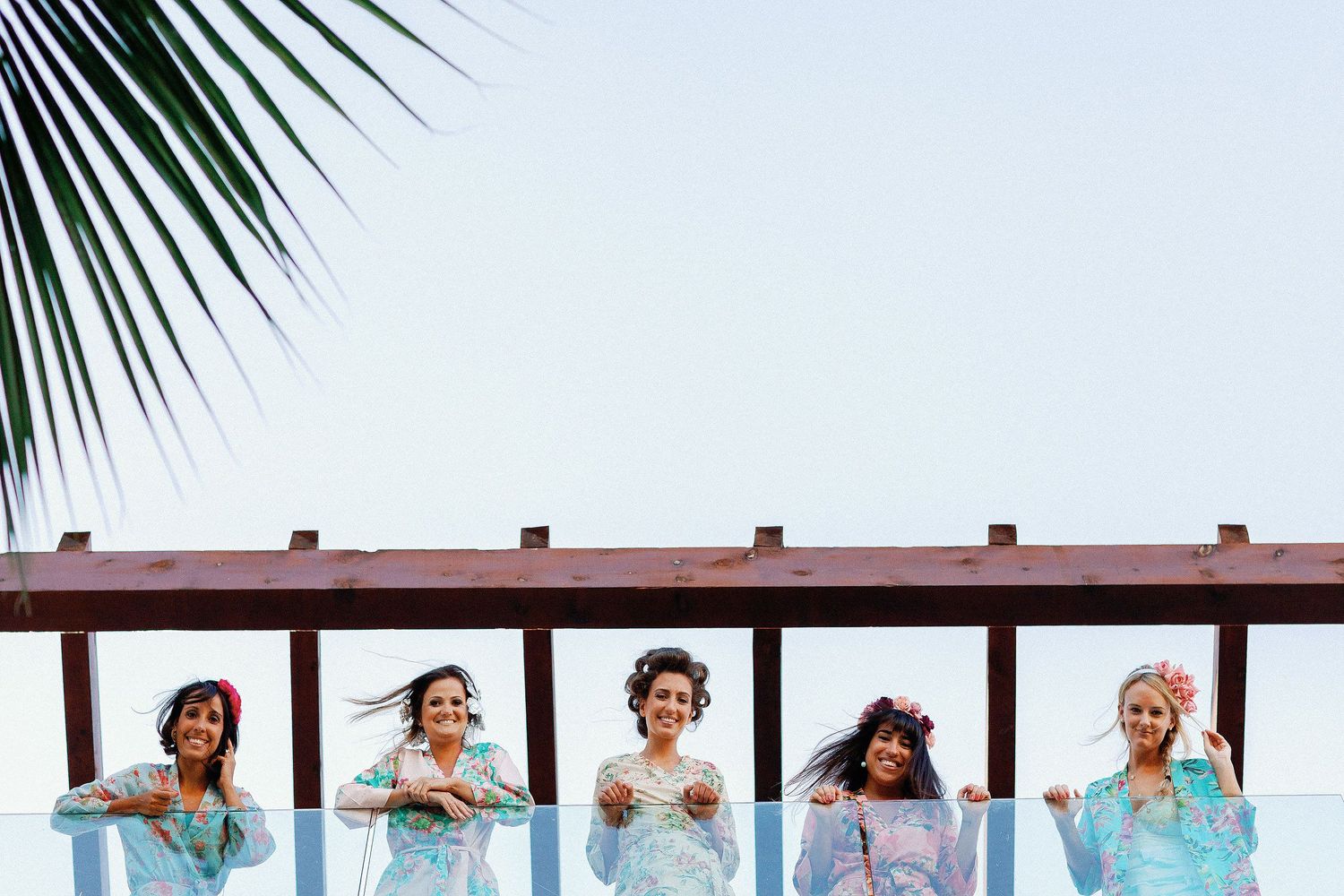 Juliana and her bridesmaids wearing floral robes on a balcony at The Elements.