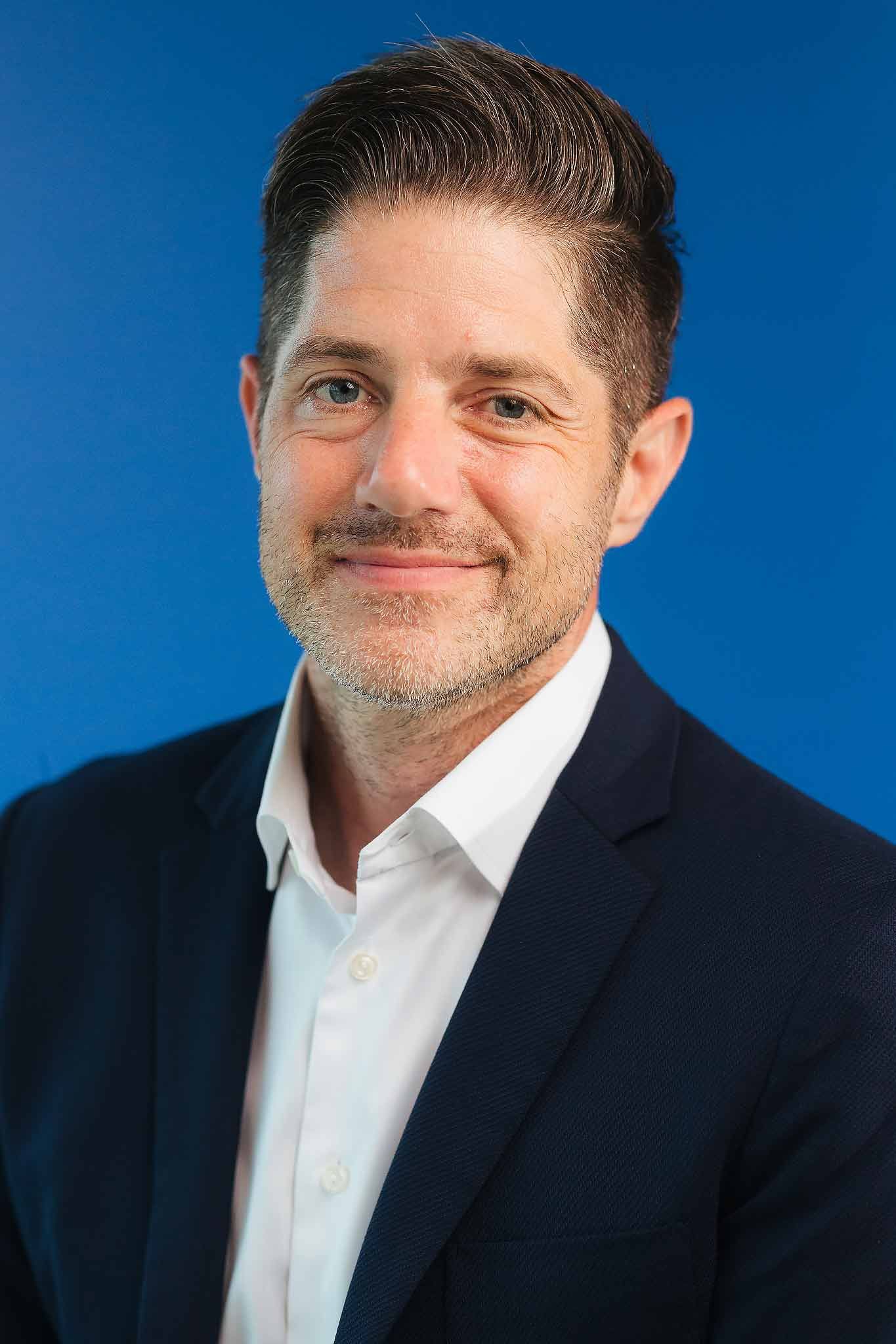 Corporate headshot photography Cancun featuring professional business portrait of man on blue background