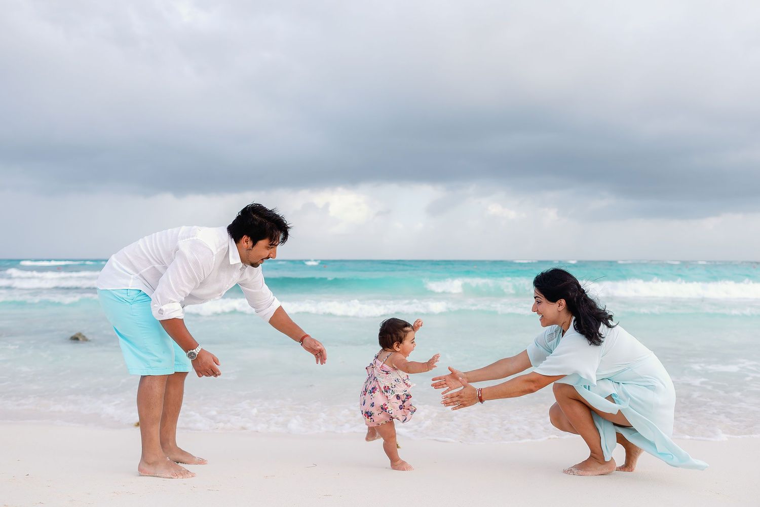 Family wearing light tropical beach outfits during a playful family photo session at Xpu-Ha Beach near Barceló Riviera Maya.