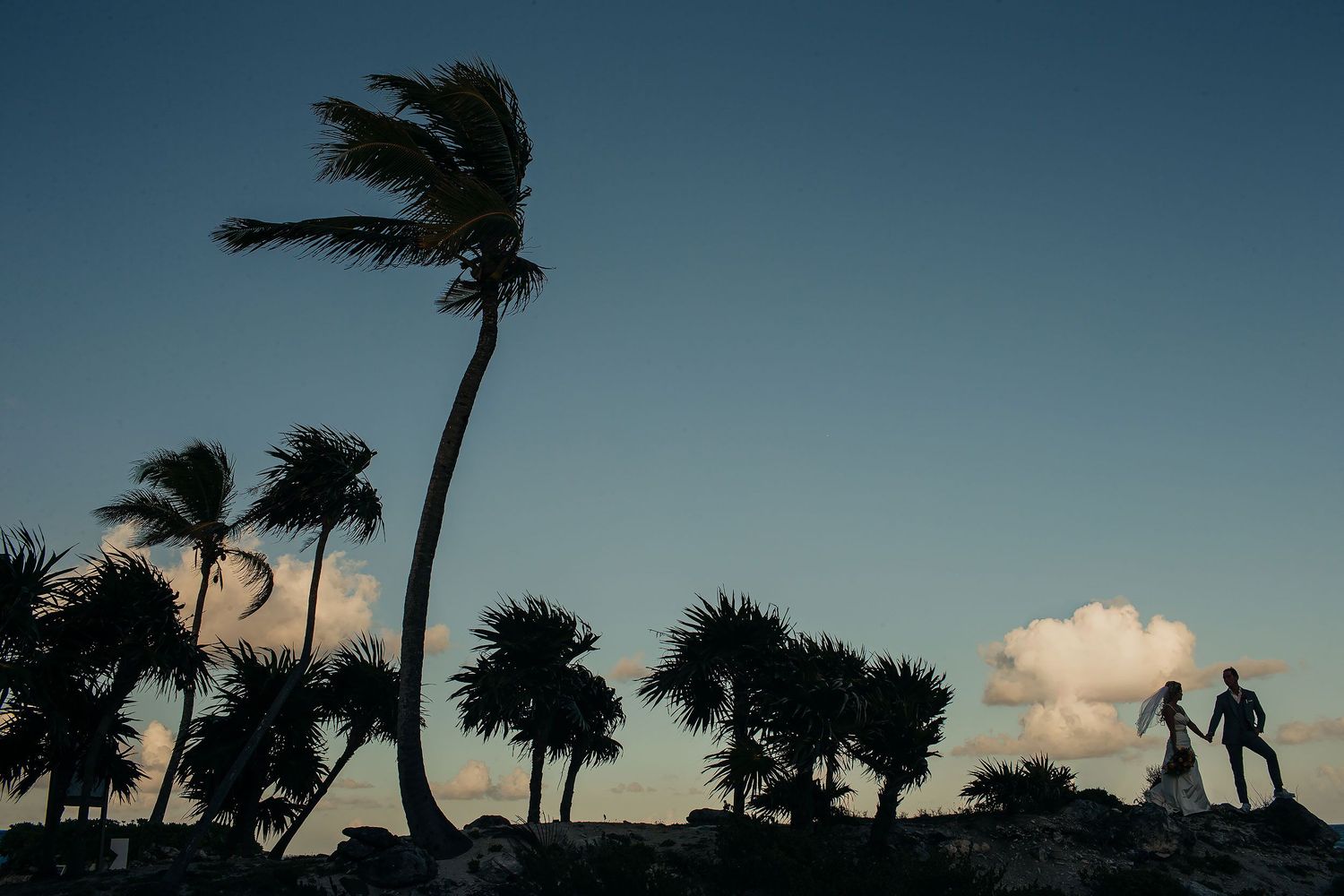 Carly and Scott beneath windswept palm trees on the Riviera Maya coast