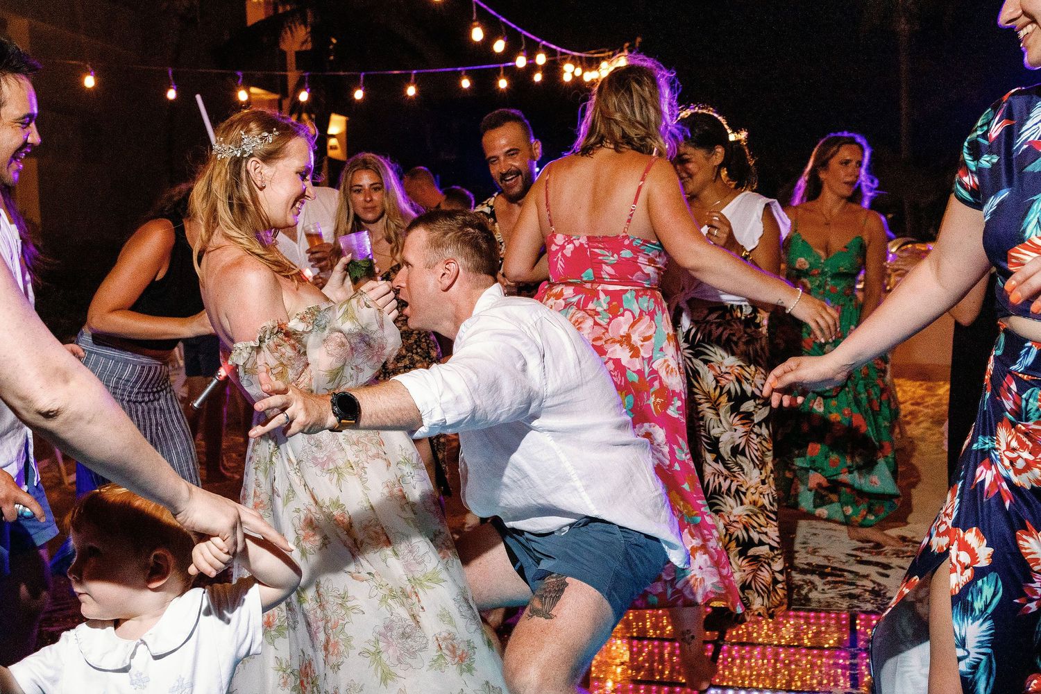 Autumn and Brian dancing playfully with their guests during their relaxed Dreams Sapphire beach reception.
