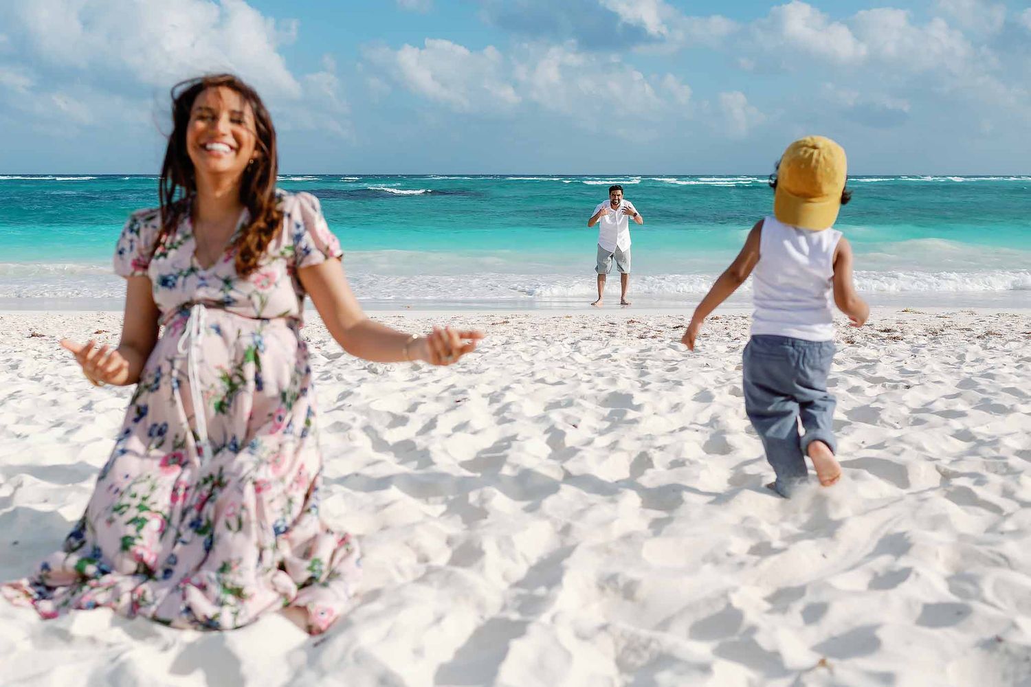 Natural family photography in Cancun capturing candid beach moments with parents and child during a sunny vacation