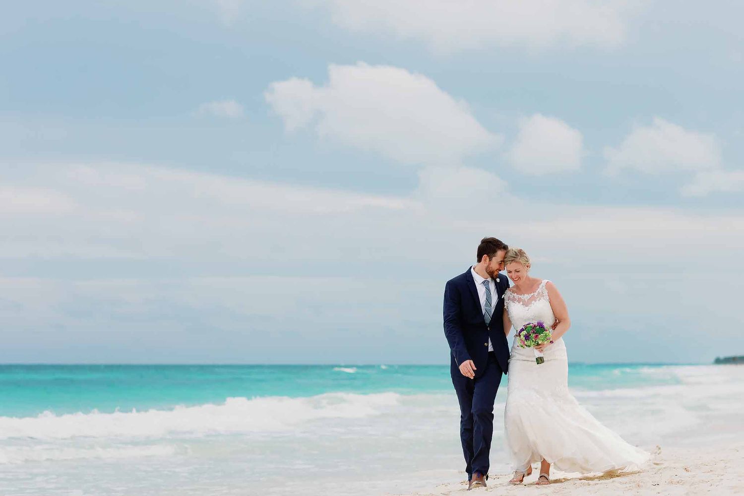 Bride and groom walking on the beach in Playa del Carmen with turquoise Caribbean ocean, destination wedding photography