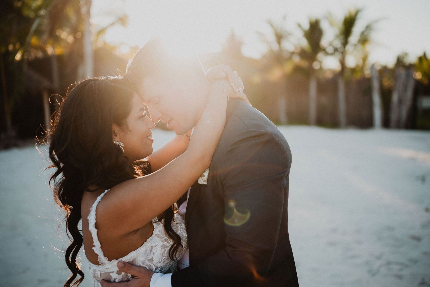 Bride and groom embracing in warm sunset light during their beach wedding portrait session at Secrets Moxché Playa del Carmen.