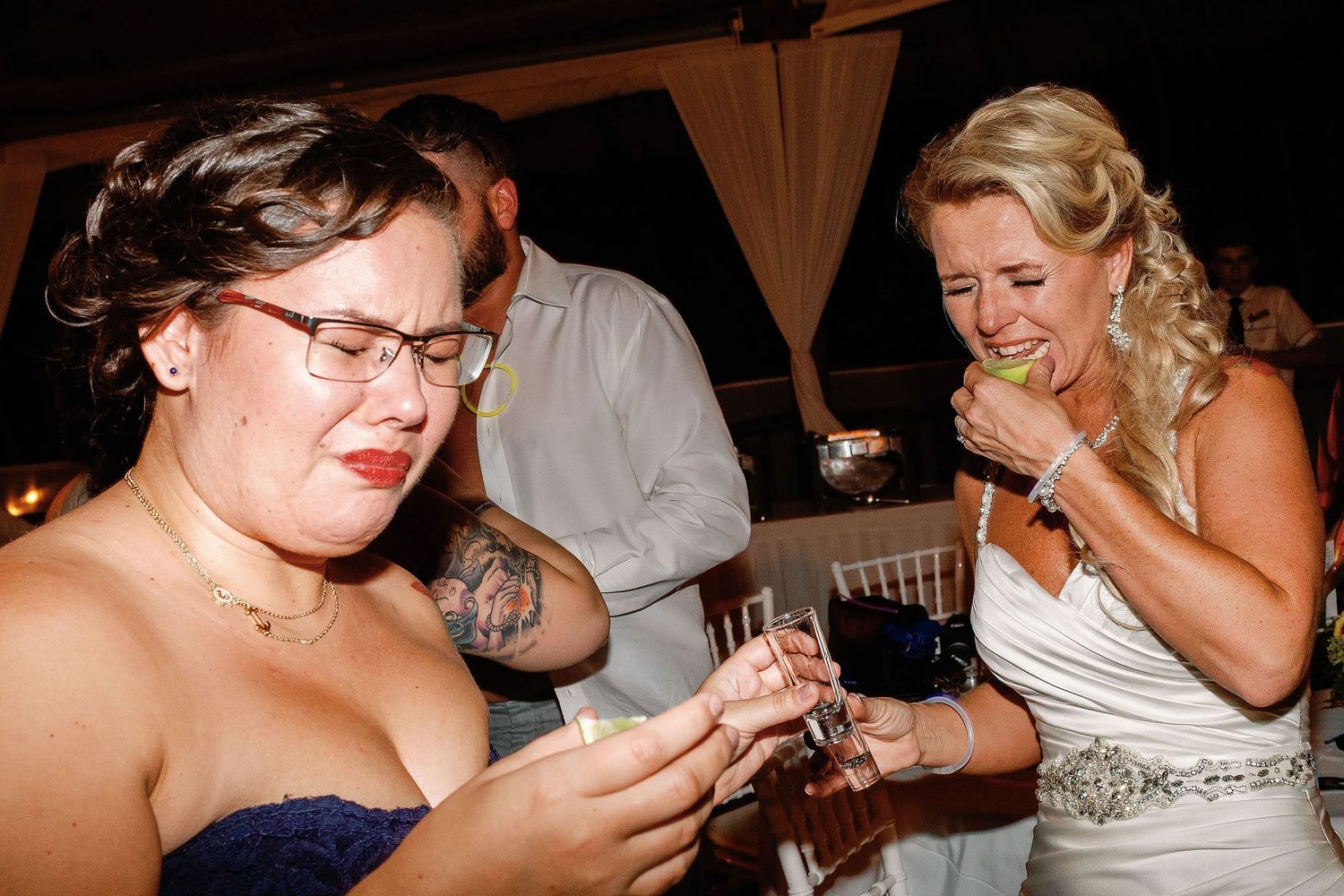 Carly and a wedding guest reacting after taking a celebratory shot