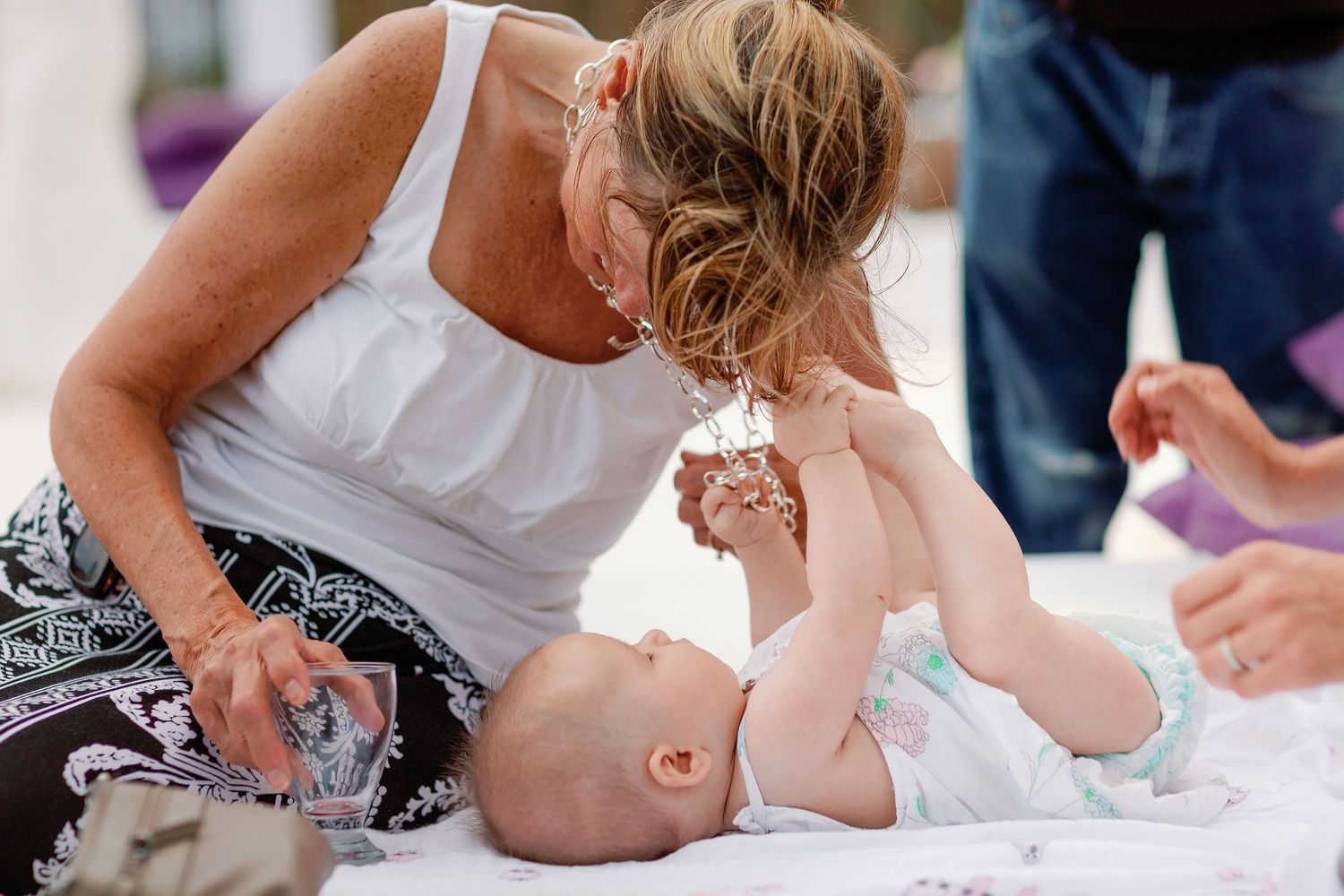 A wedding guest shares a playful moment with a baby during the daytime beach-club reception.