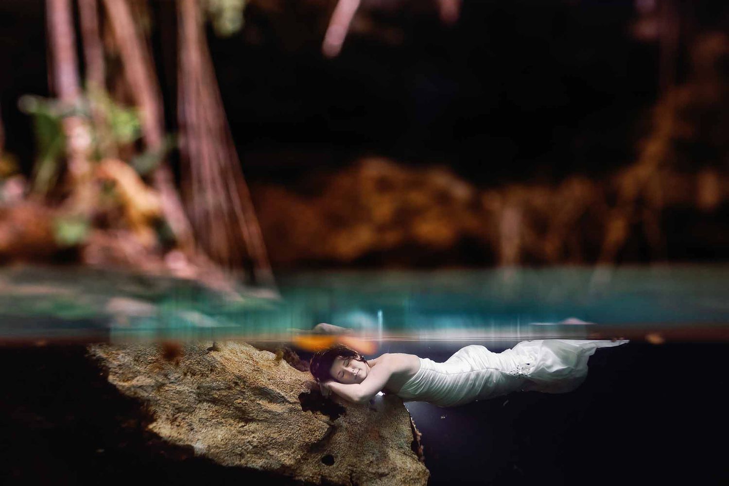 Bride floating underwater in a Riviera Maya cenote during a fine art underwater wedding portrait session in Mexico.