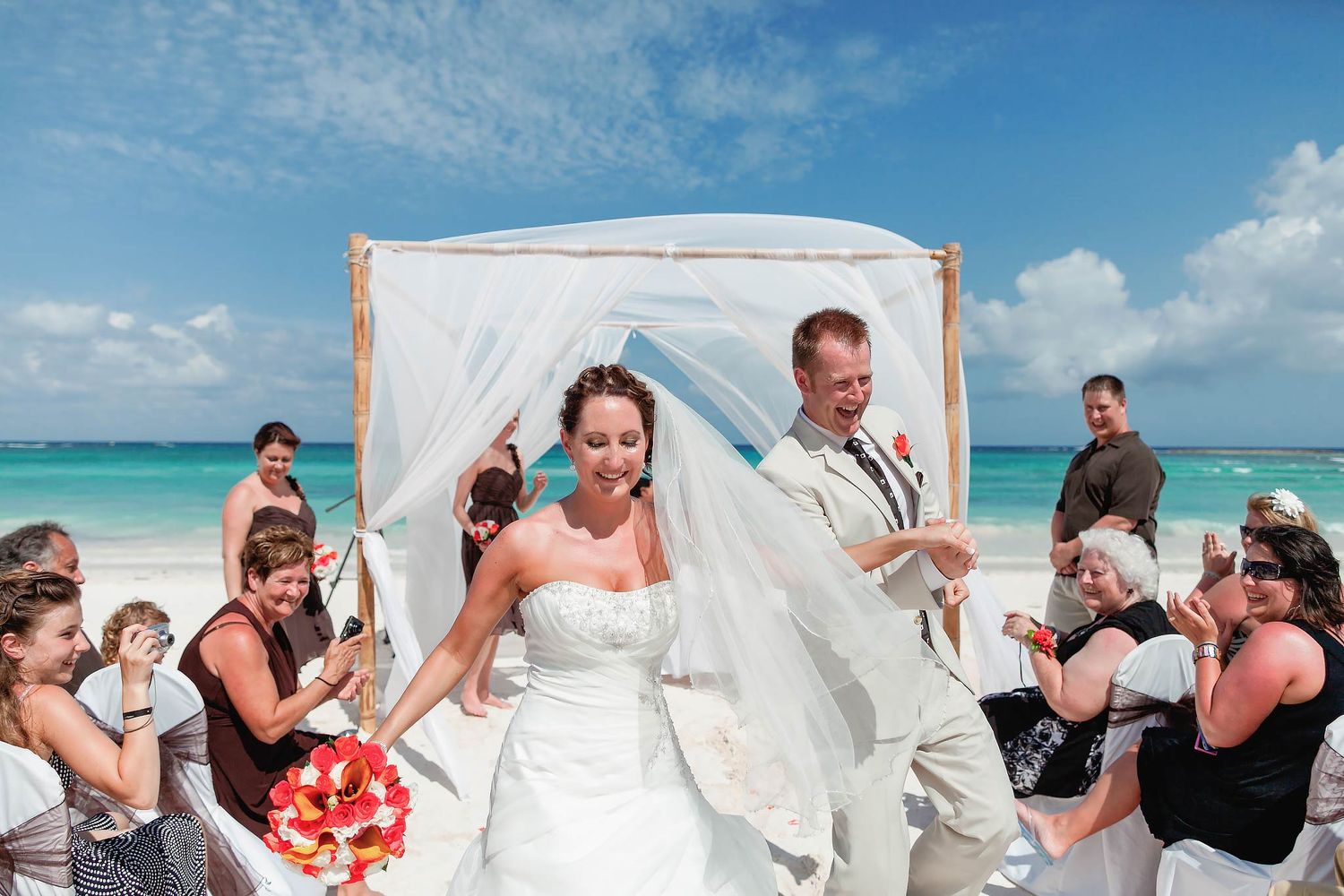 Joyful beach wedding ceremony at Excellence Playa Mujeres. Professional destination wedding photographer for luxury Cancun events.