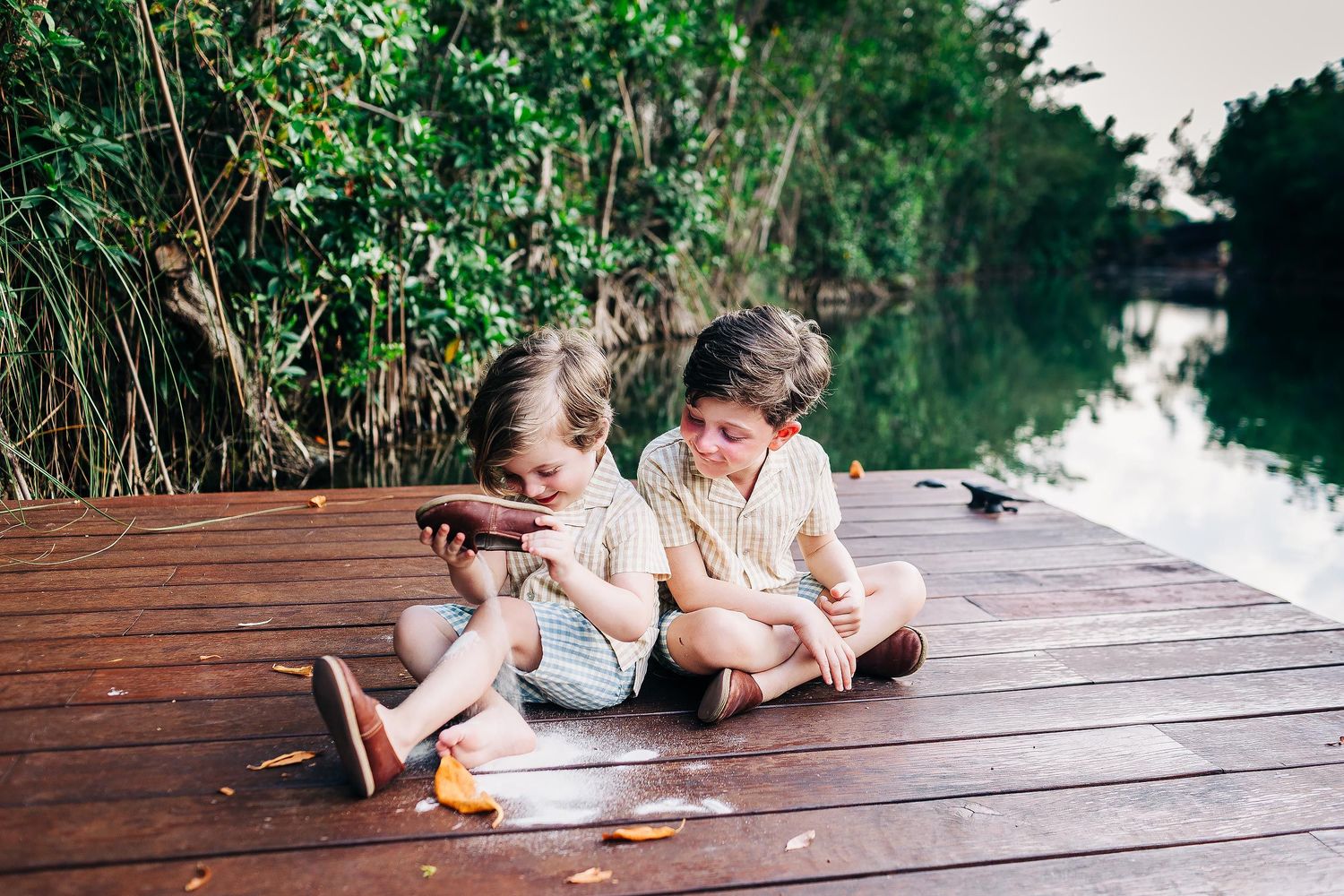Brothers sitting together on a wooden dock during a family photography session in Riviera Maya.