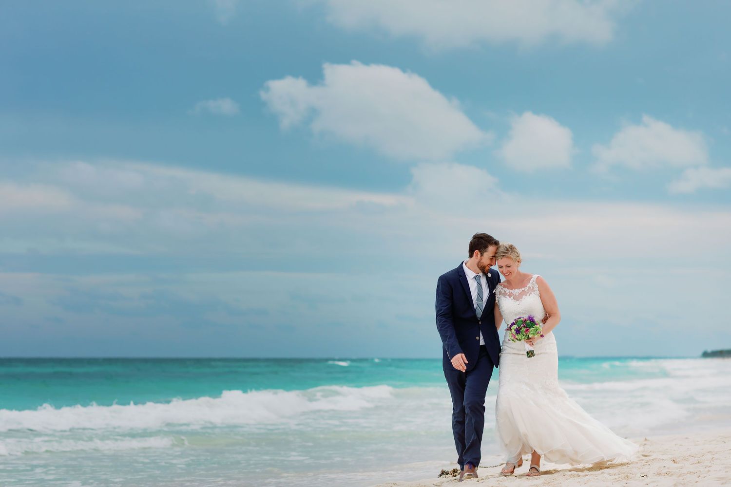 Ashley and Matt walk together beside the turquoise Caribbean after their Tulum beach wedding.