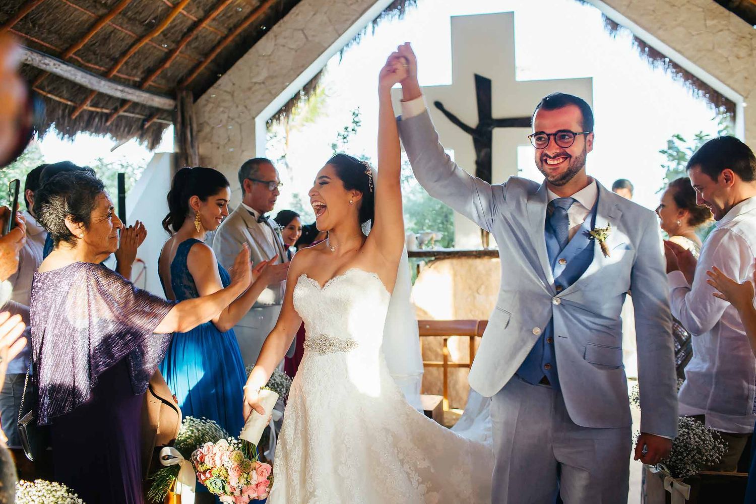 Bride and groom celebrating after Catholic beach wedding ceremony at Jardín del Mar Chapel in Cancun