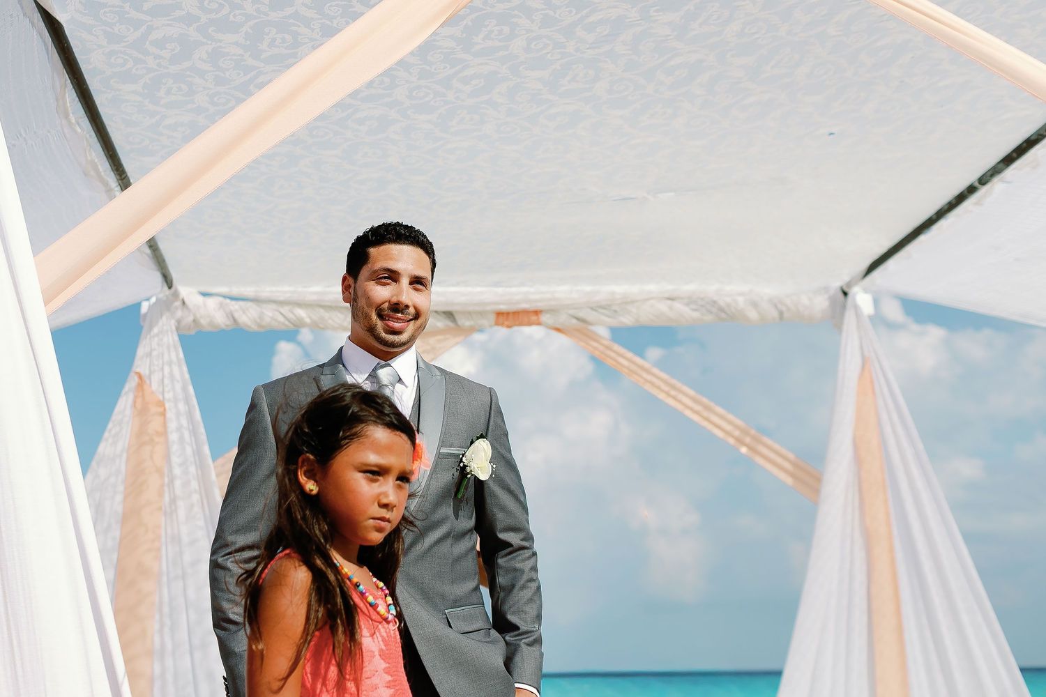 Keith waits beneath the fabric-draped ceremony canopy on the beach.