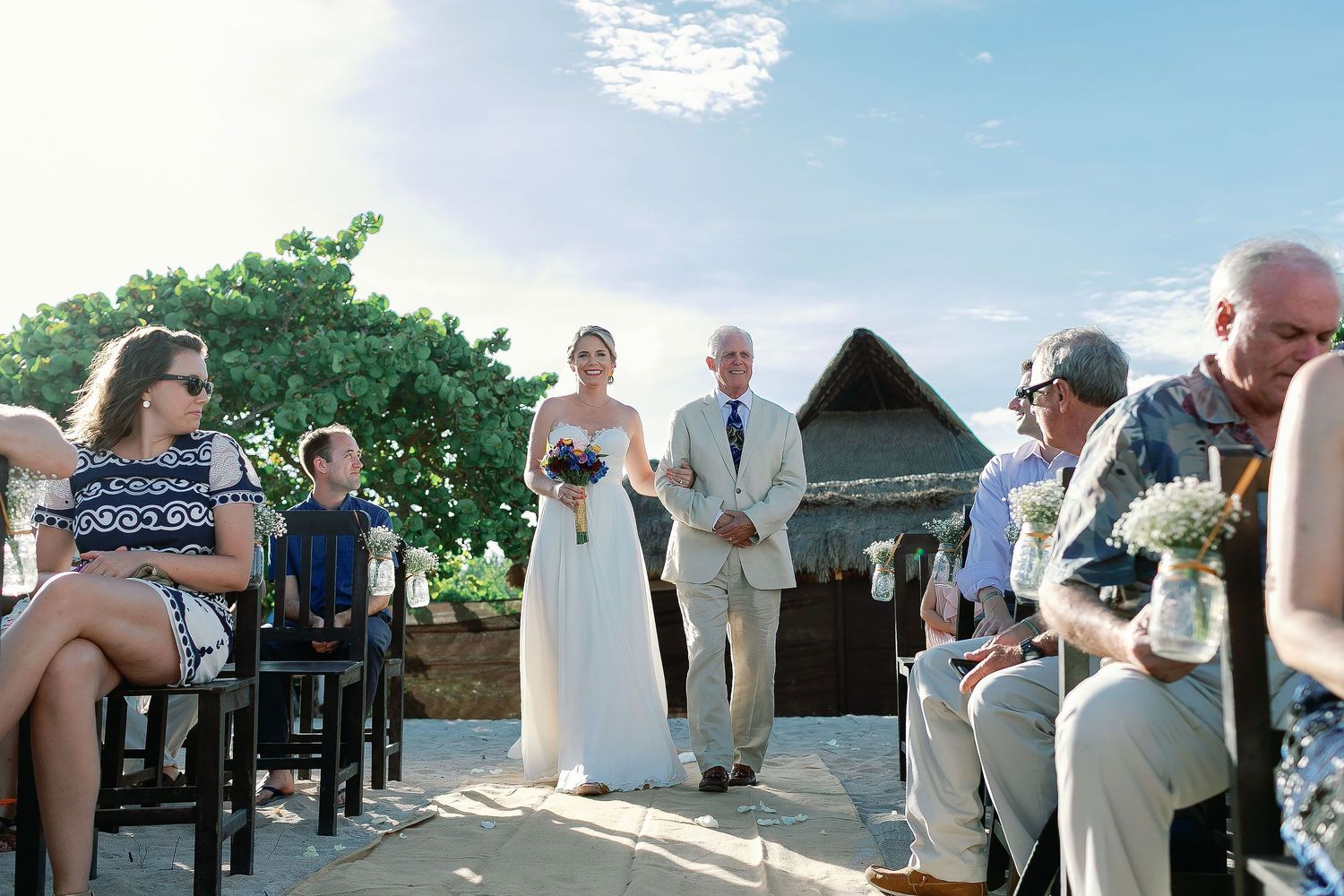 Cressida walking down the sandy aisle with a loved one during her private beach wedding ceremony in the Riviera Maya.