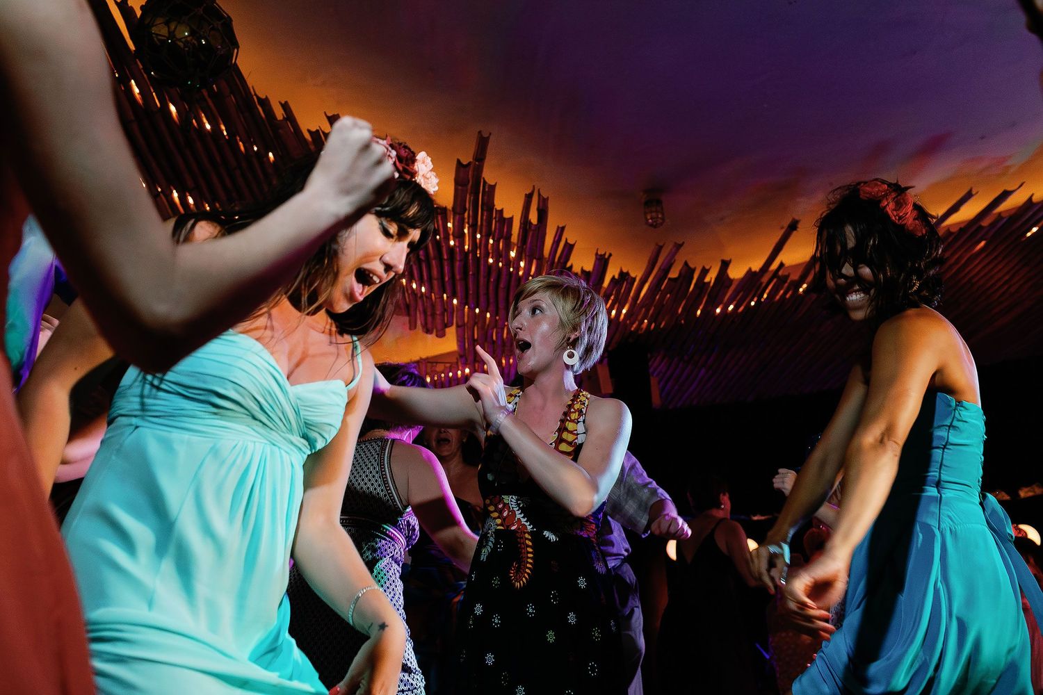Bridesmaids in turquoise dresses dance together during the lively wedding reception.
