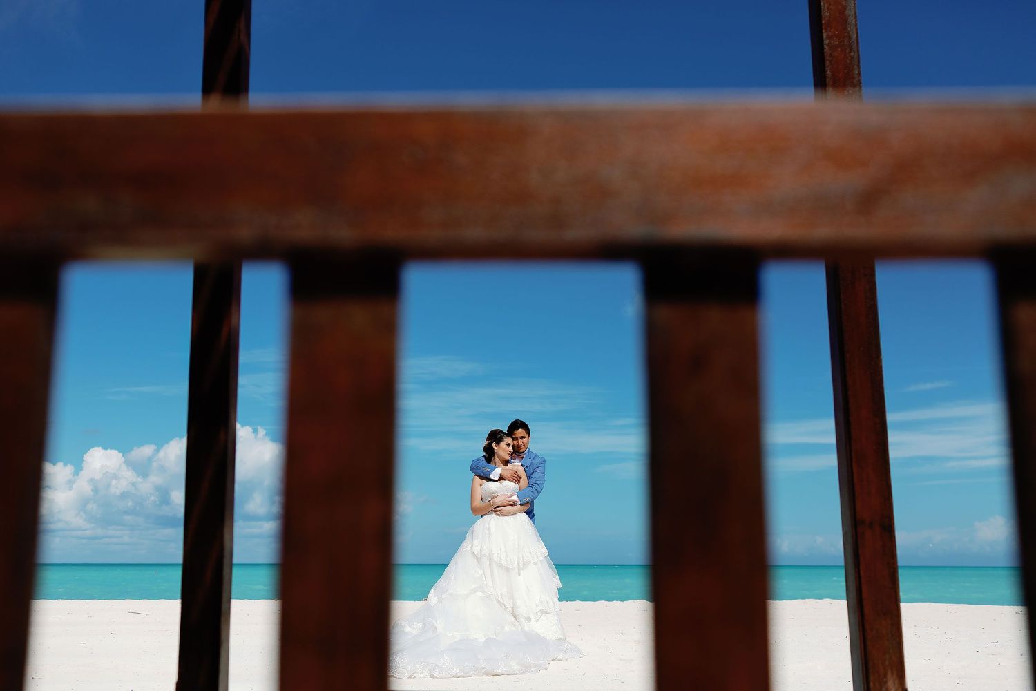 Bride and groom embracing on a white sand beach in Cozumel with turquoise Caribbean waters in the background