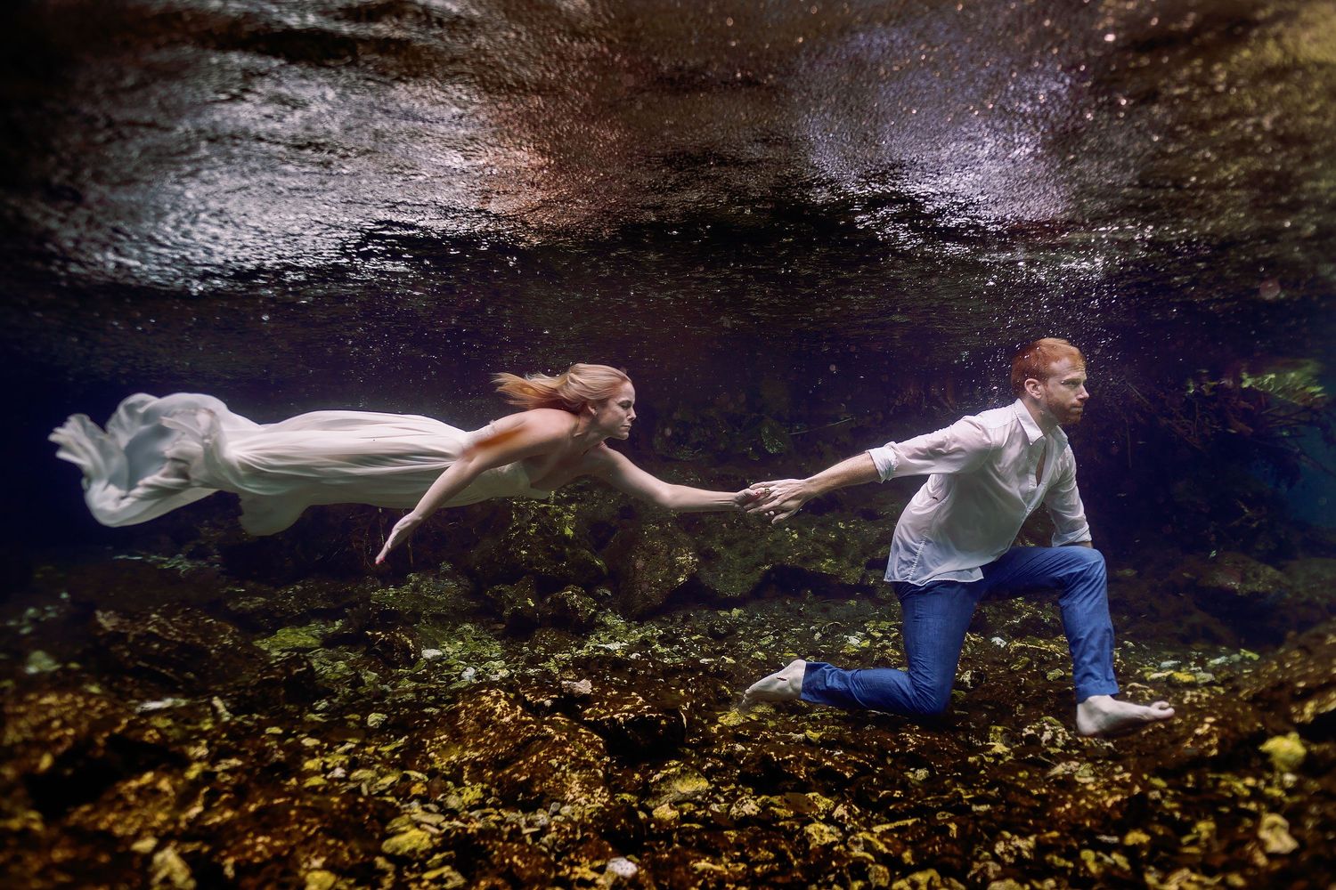 Cressida and Alan holding hands underwater during their Trash the Dress photography session at Gran Cenote in Tulum.