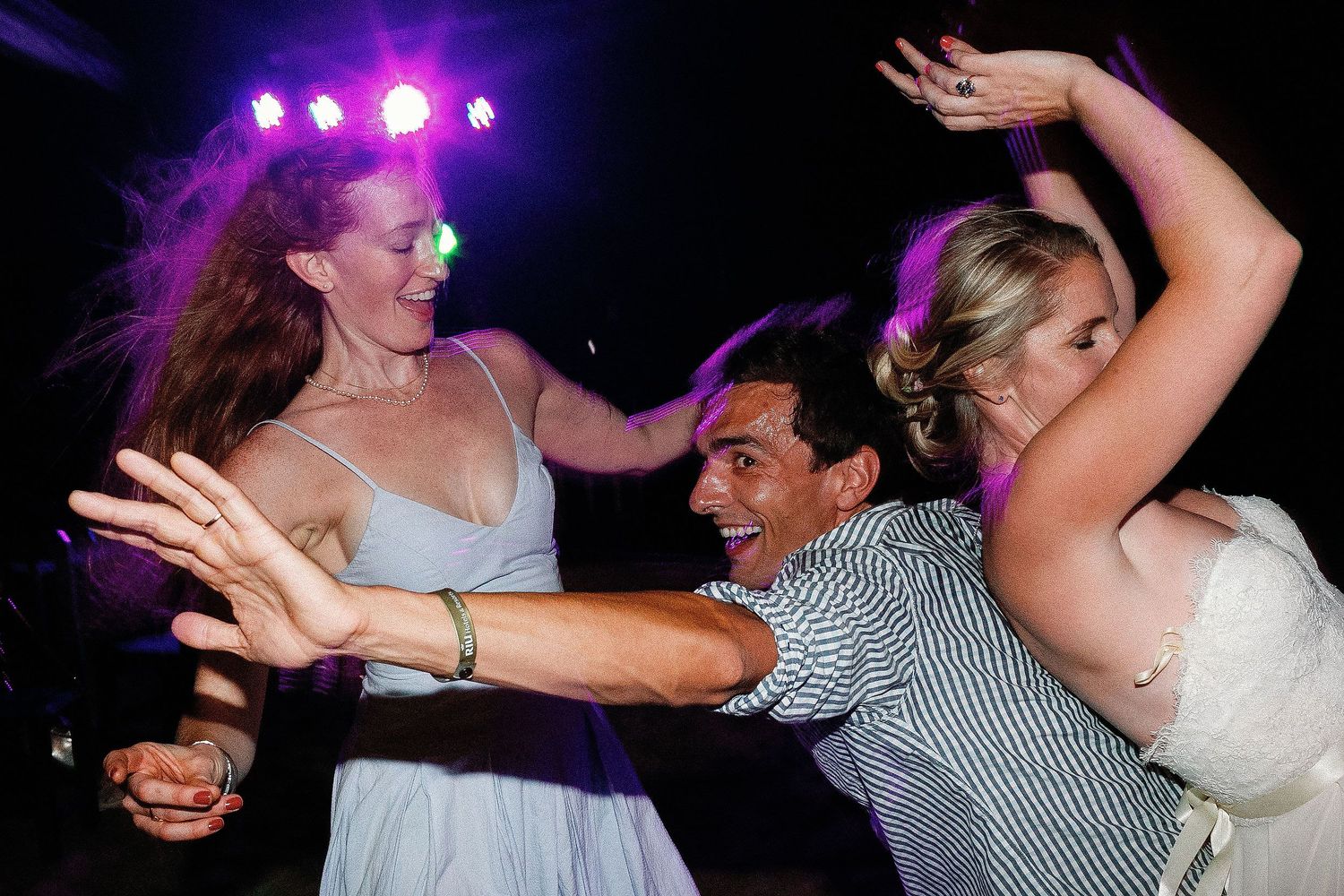 Cressida dancing with wedding guests beneath colorful reception lights at a private Riviera Maya venue.
