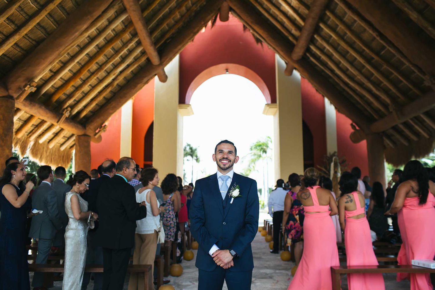 Groom waiting at Catholic wedding ceremony in Xoximilco Riviera Maya chapel Capilla del Niño with guests and tropical open-air setting