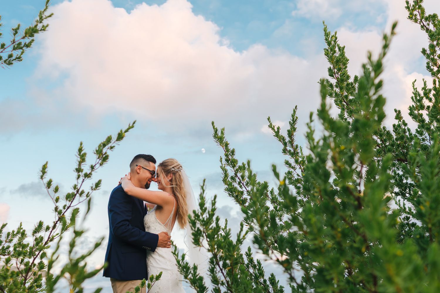 Creative wedding portrait at Grand Velas Riviera Maya surrounded by tropical greenery and soft Caribbean sky tones.