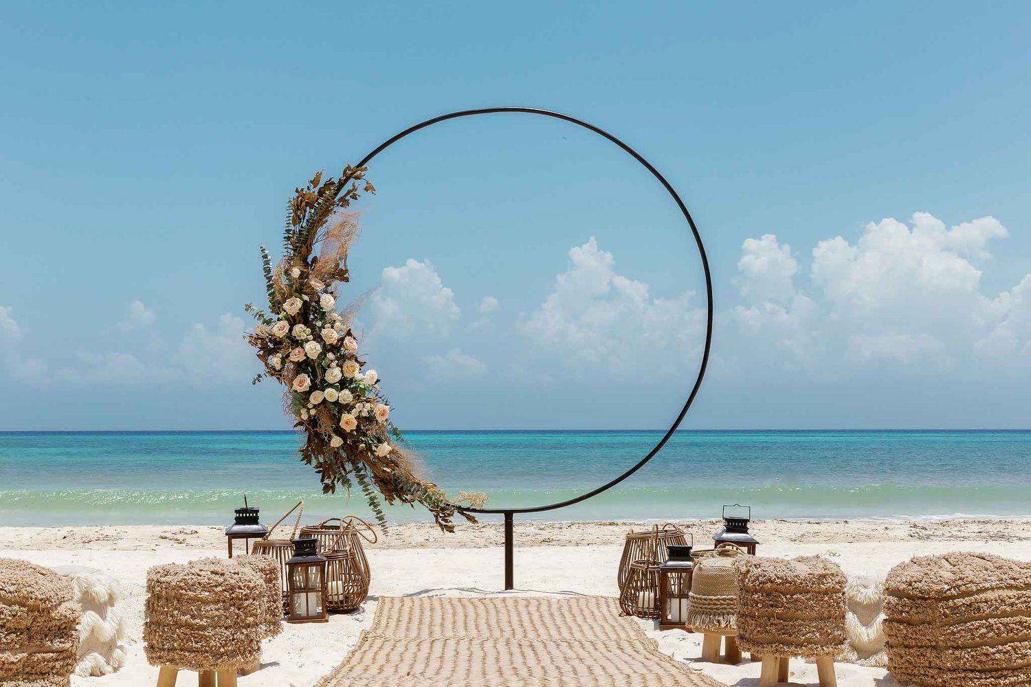 Boho beach wedding ceremony setup with circular arch and floral design in Playa del Carmen overlooking Caribbean ocean