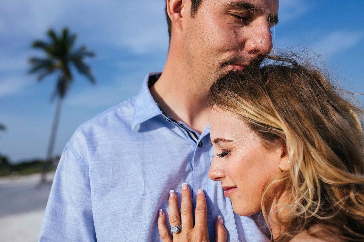 Close portrait of engaged couple showing wedding ring during a beach engagement photography session in Riviera Maya.