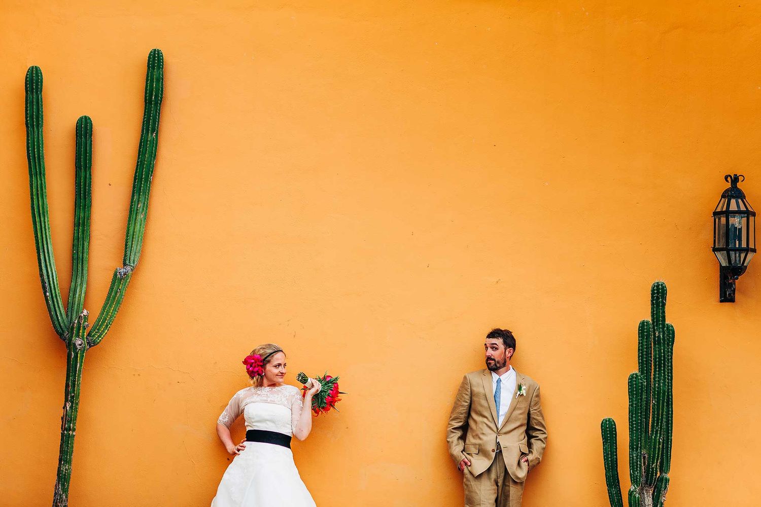 Creative destination wedding portrait at Hotel Xcaret Mexico with colorful Mexican wall and cactus scenery in Riviera Maya.