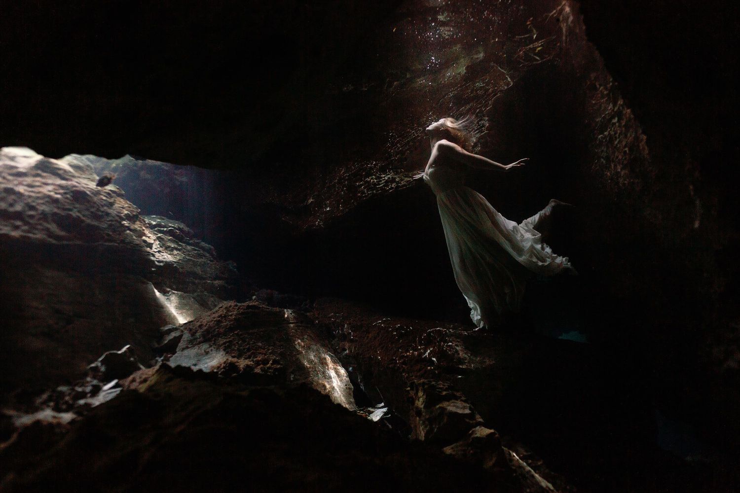 Cressida floating underwater in her wedding dress during a Trash the Dress photography session at Gran Cenote in Tulum.