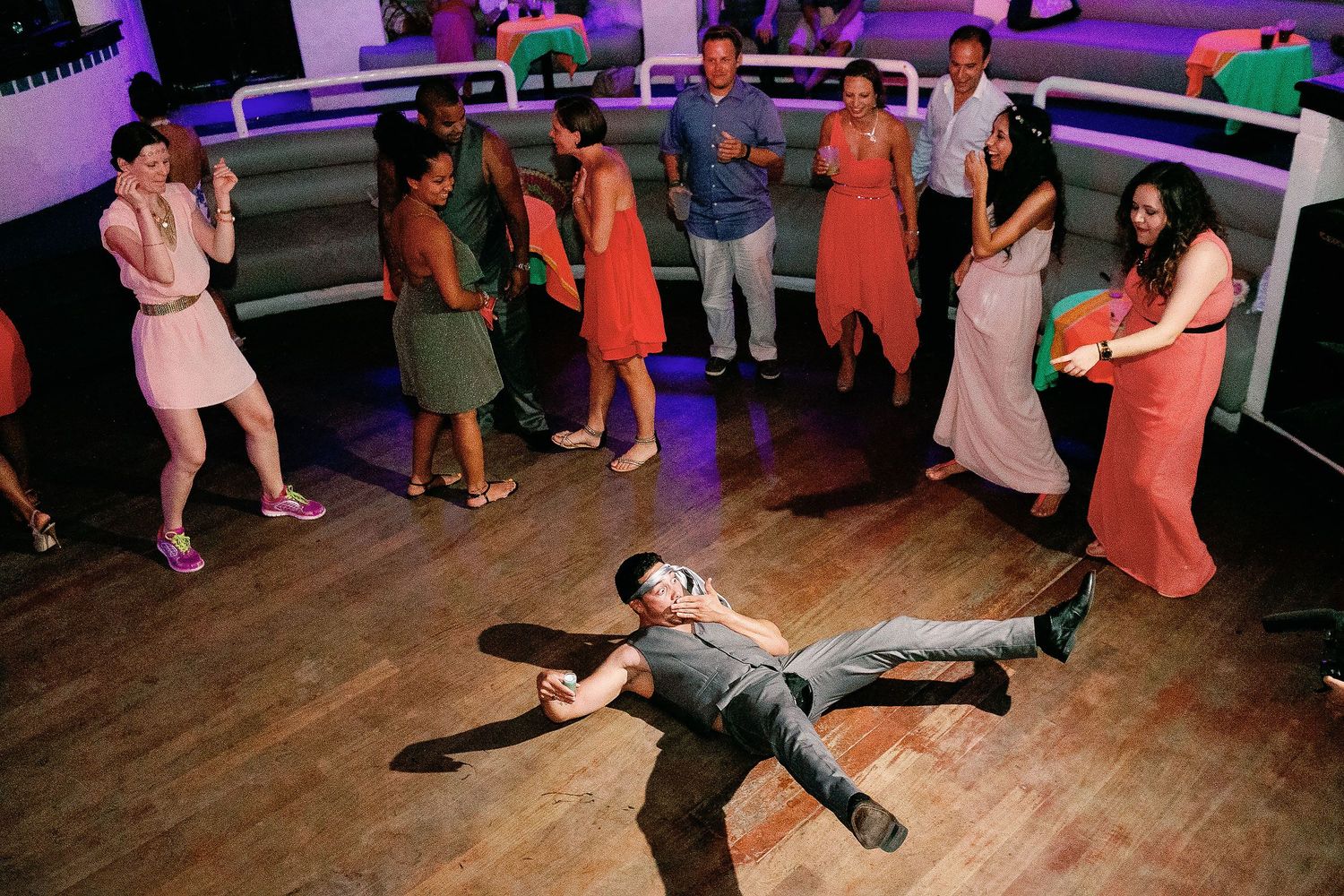 Keith the groom strikes a playful pose on the nightclub dancefloor as the wedding party dances around him.