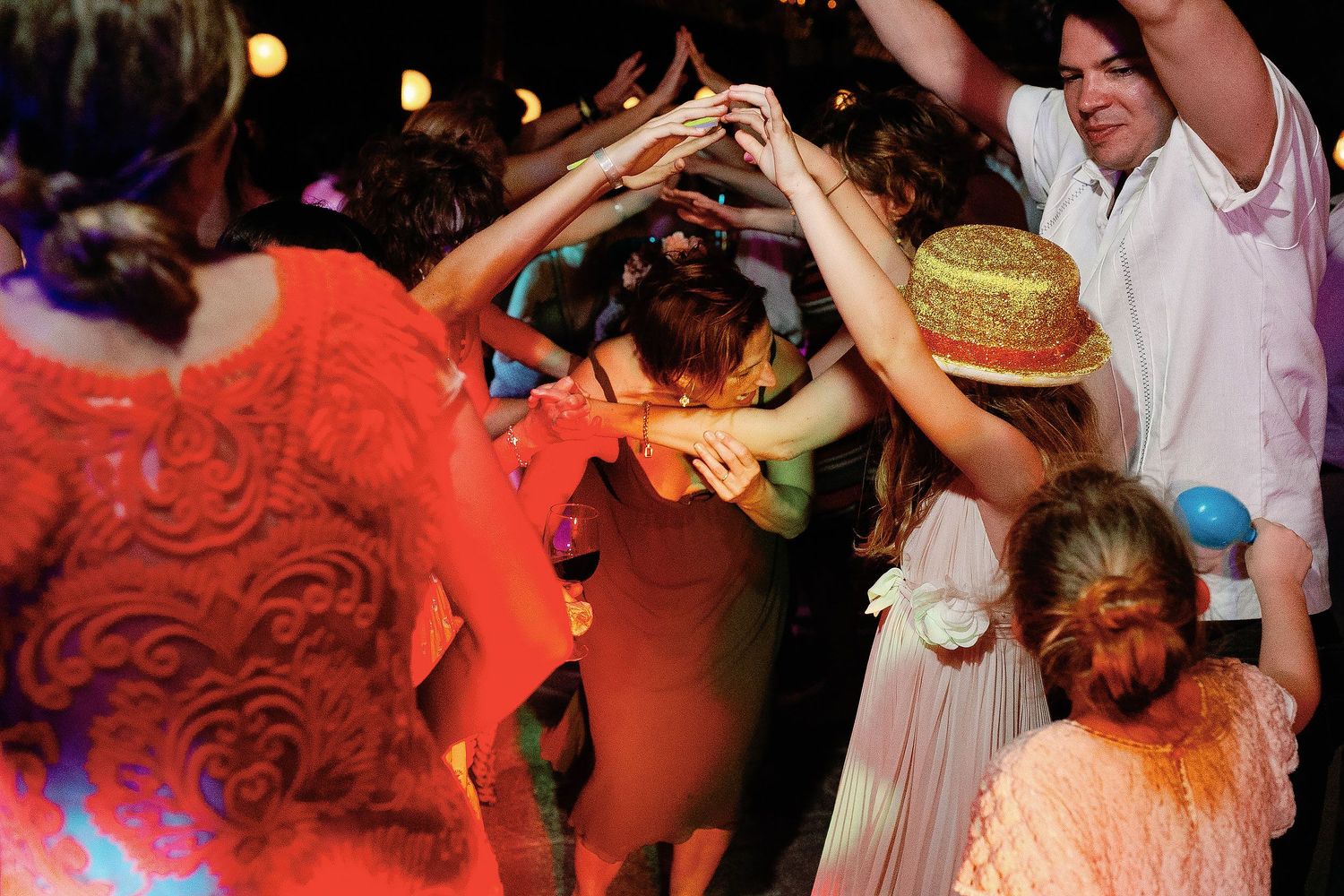 Guests raise their hands and dance beneath colorful lights at Fragata Beach Club.