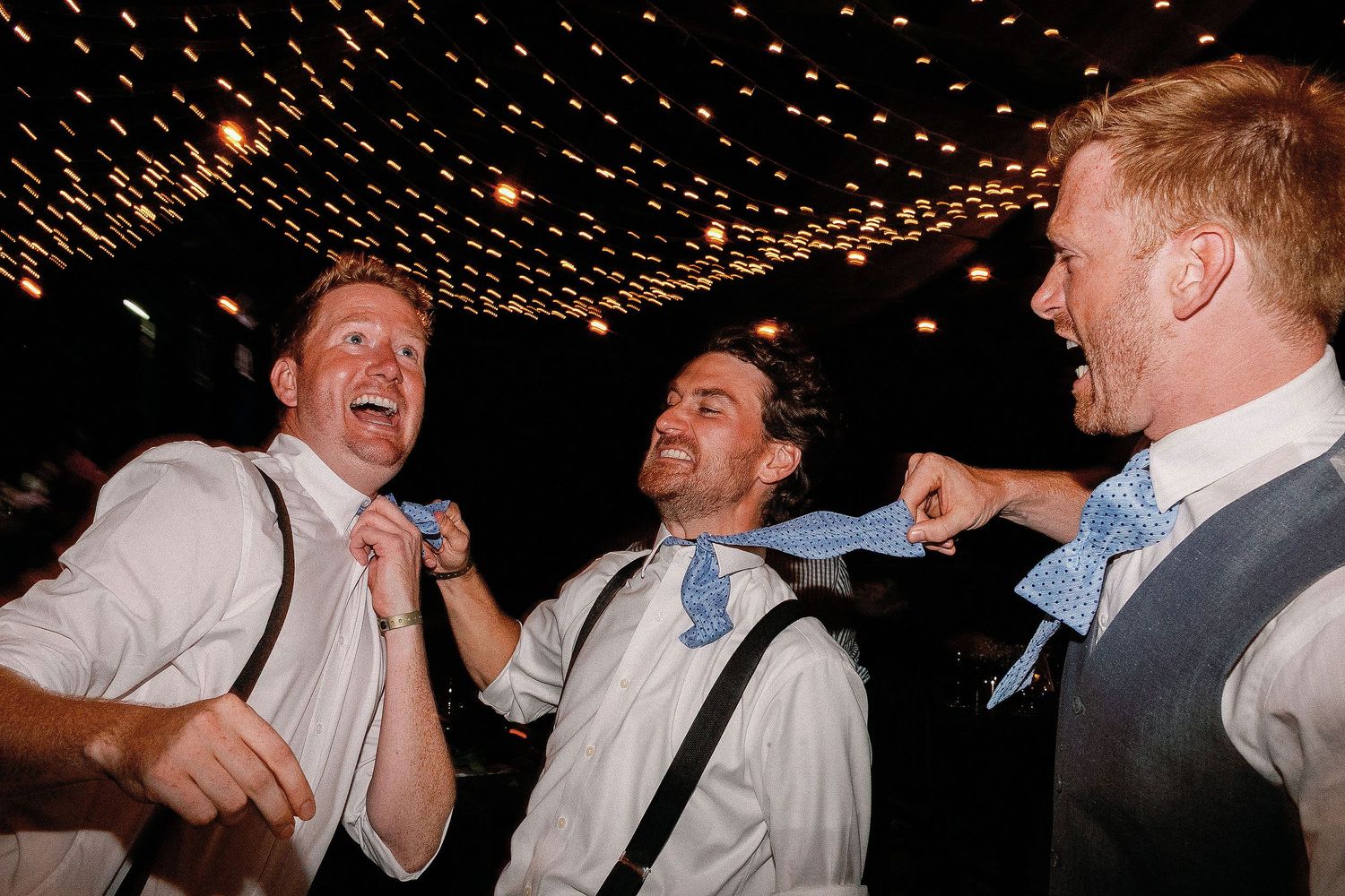 Alan and two groomsmen joking with their blue bow ties during the private Riviera Maya wedding reception.
