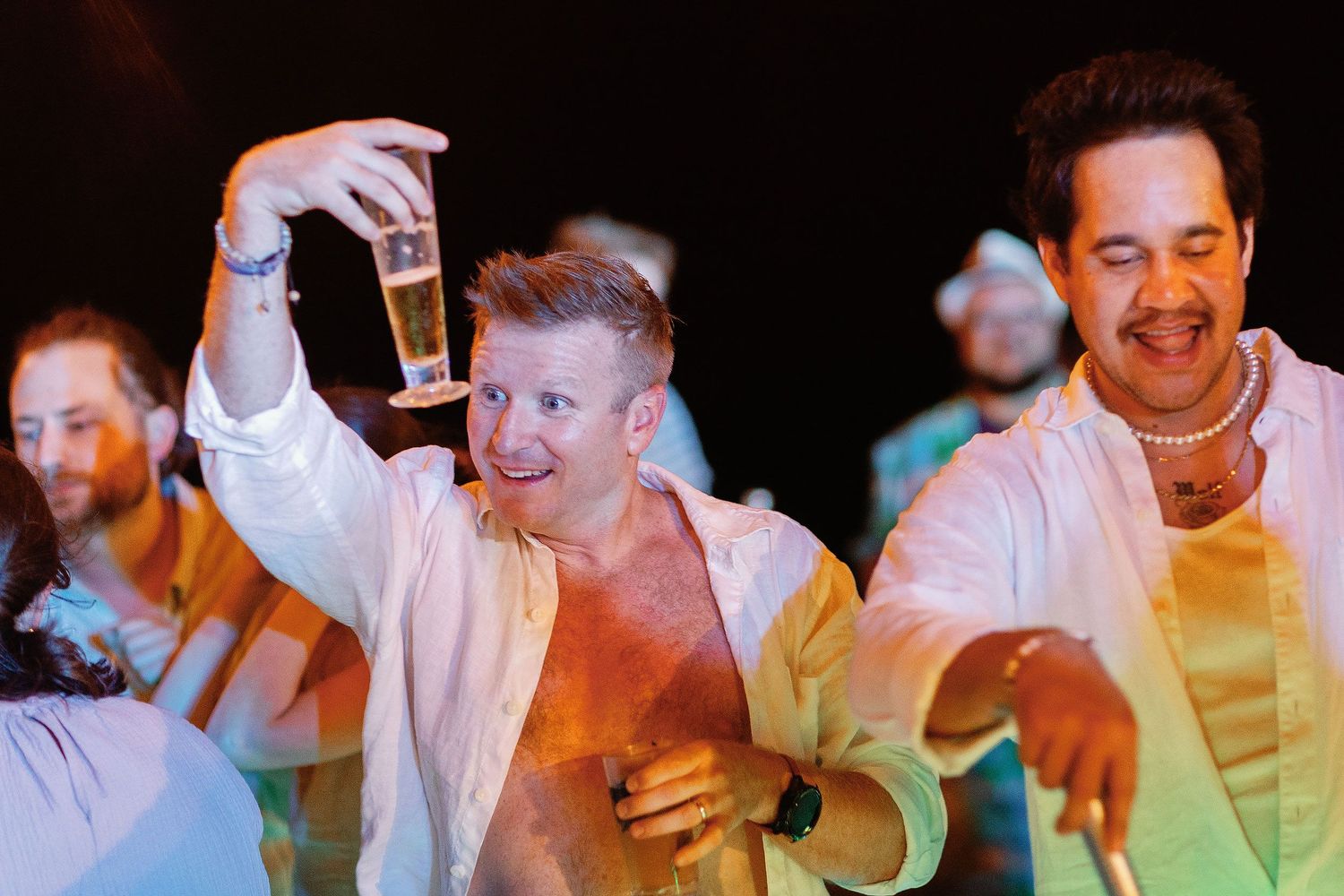 Brian raising his drink while dancing with guests during the relaxed Dreams Sapphire beach reception.