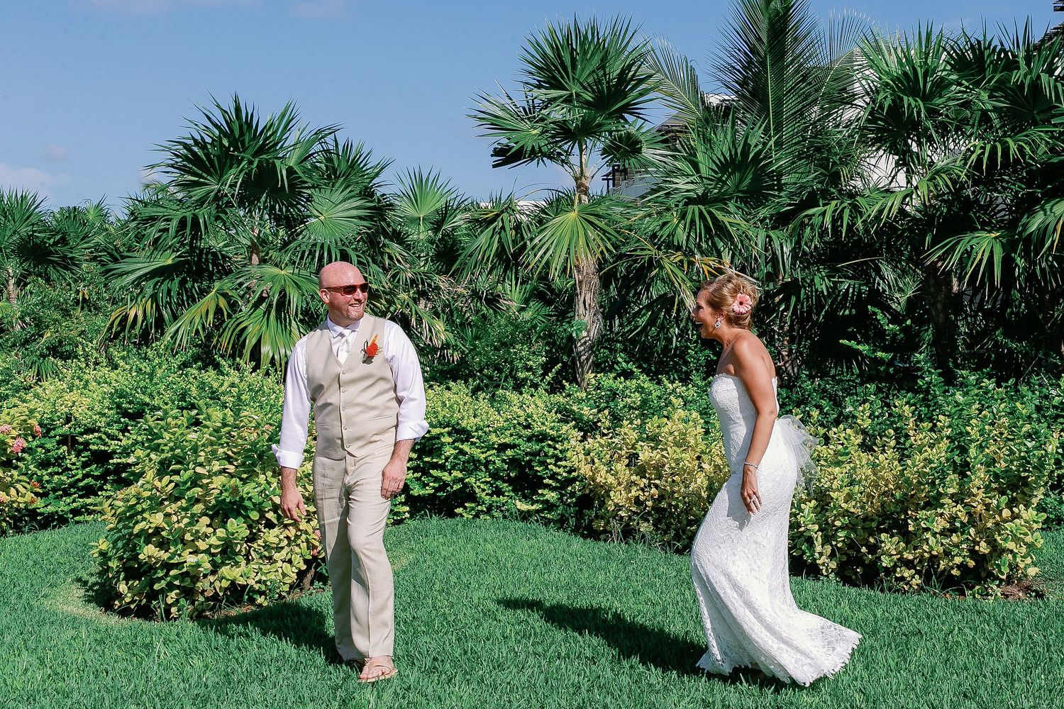 Bride laughing as the groom turns to see her during their wedding first look in the tropical gardens at Secrets Maroma Beach Riviera Cancun.