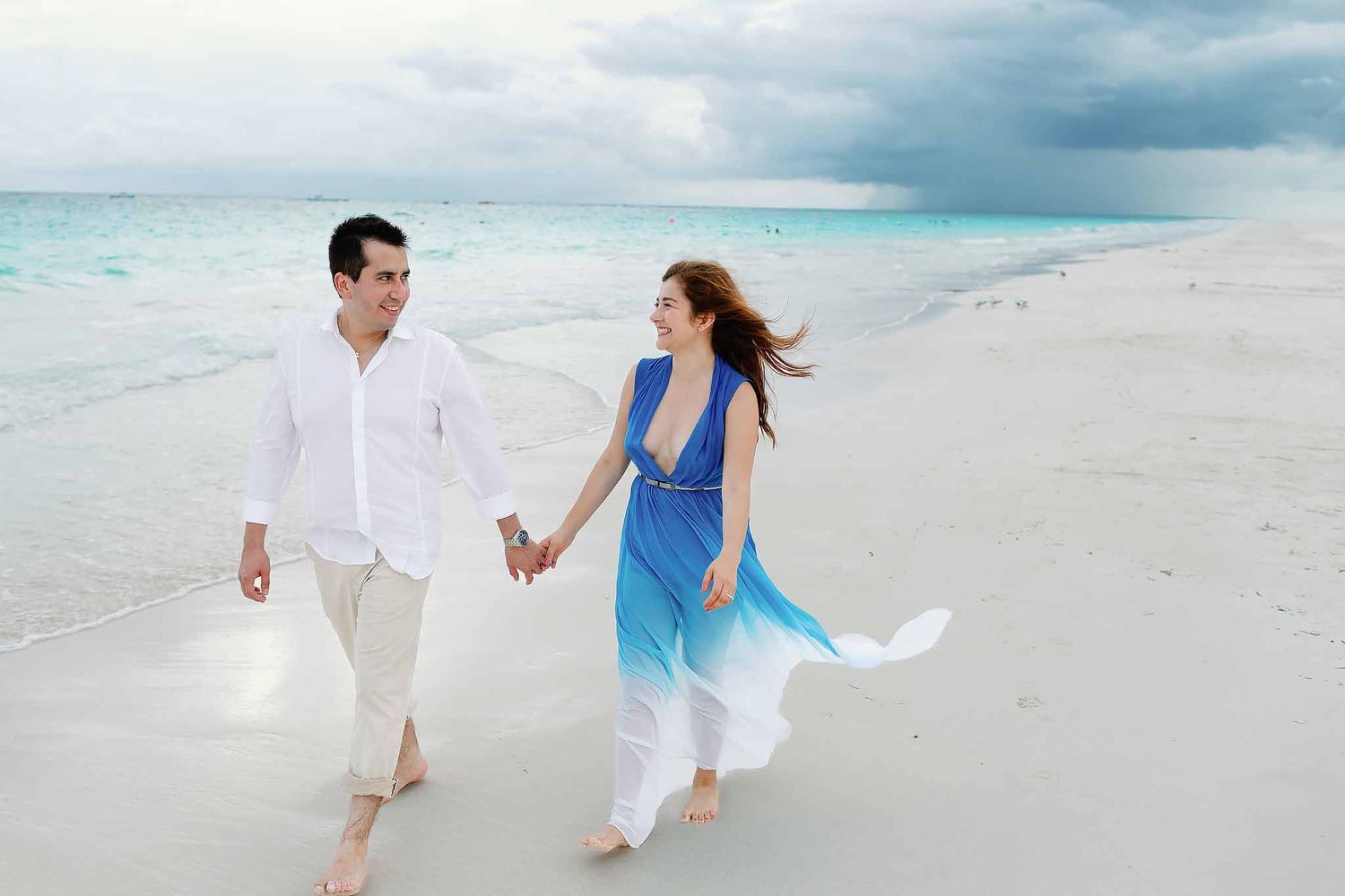 Romantic Cancun beach engagement session with couple walking along the turquoise shoreline in Riviera Maya Mexico