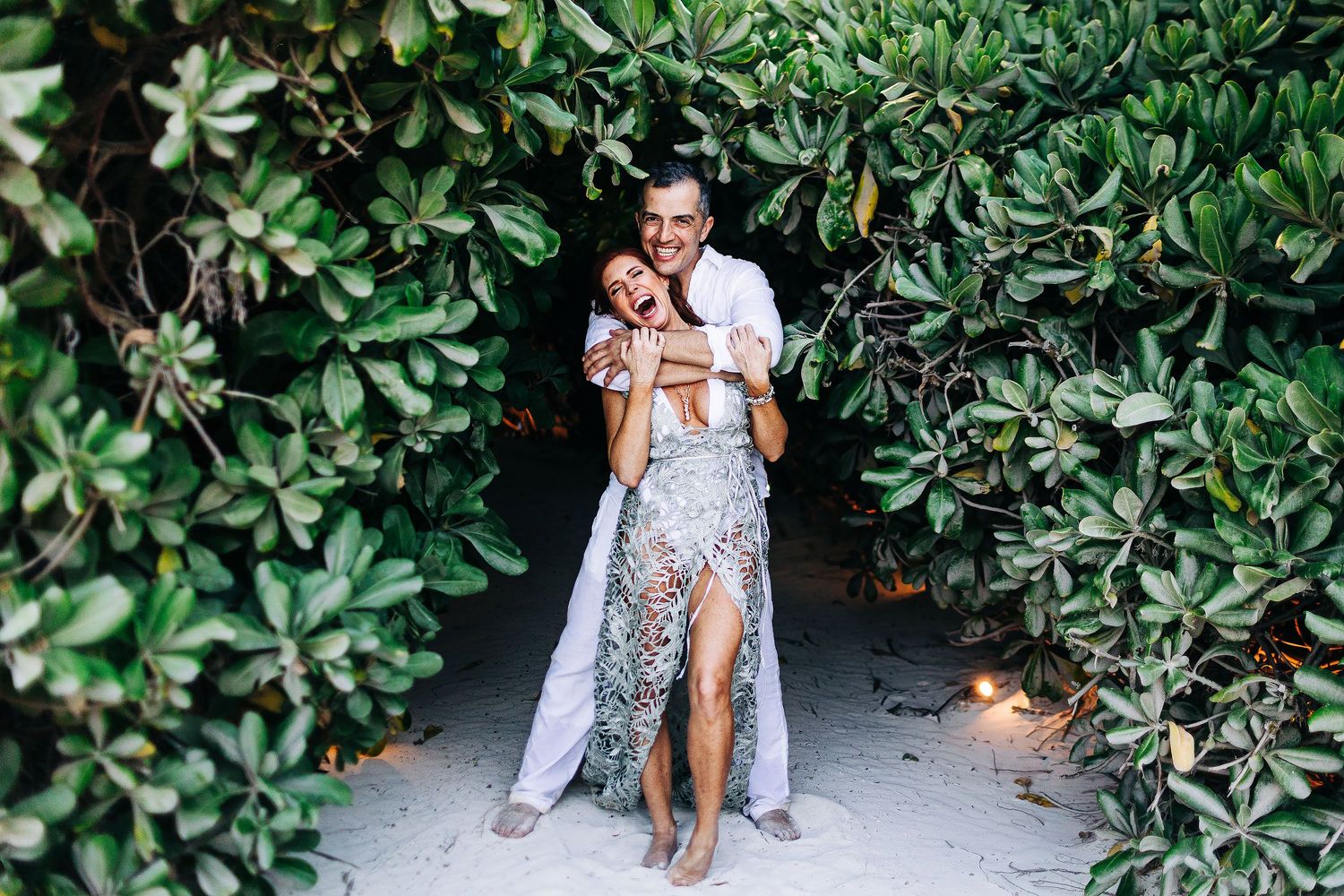 Evish hugs Sarah as they laugh inside a tunnel of tropical greenery