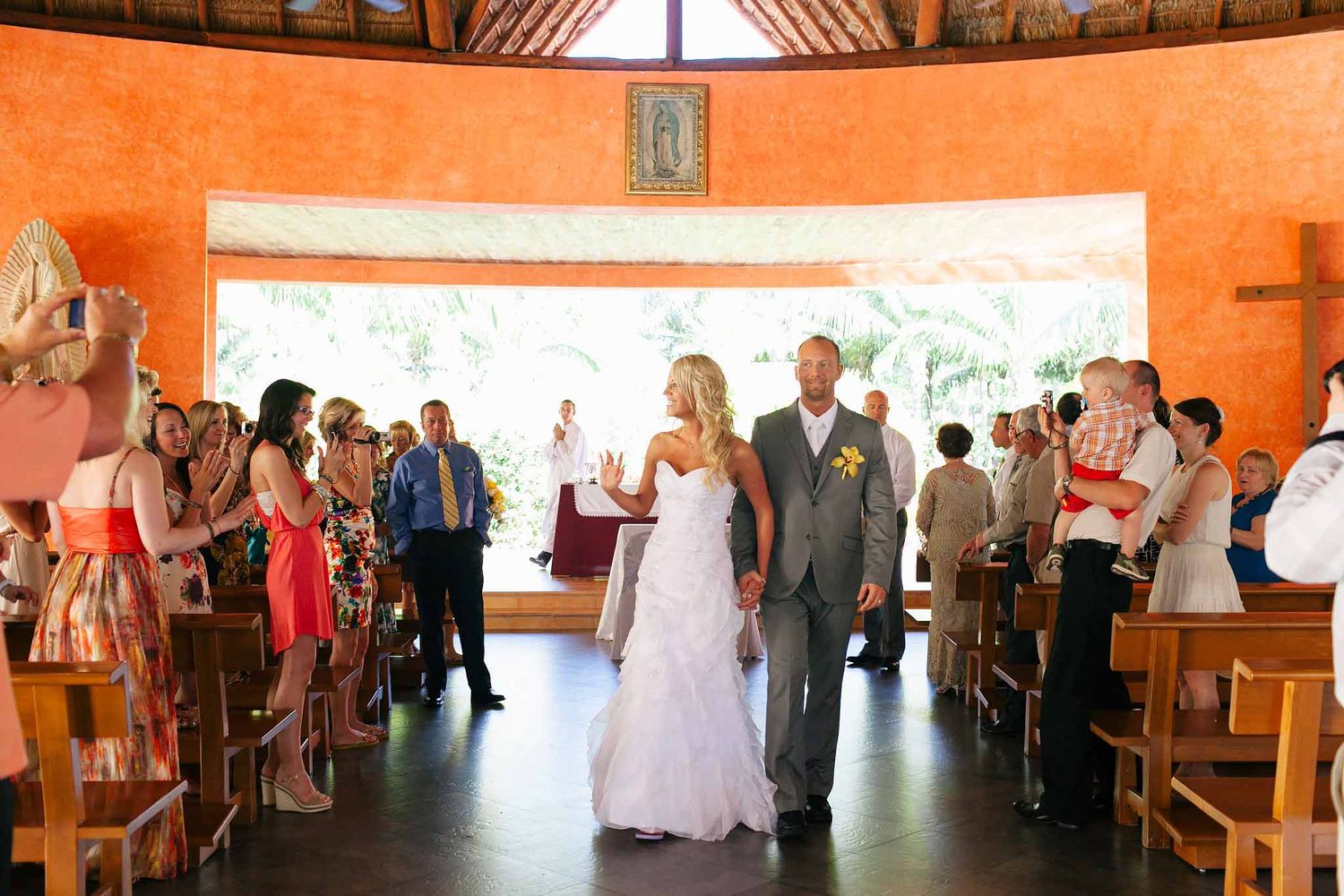 Bride and groom exiting Our Lady of Guadalupe Chapel Barceló Riviera Maya after Catholic wedding with guests celebrating
